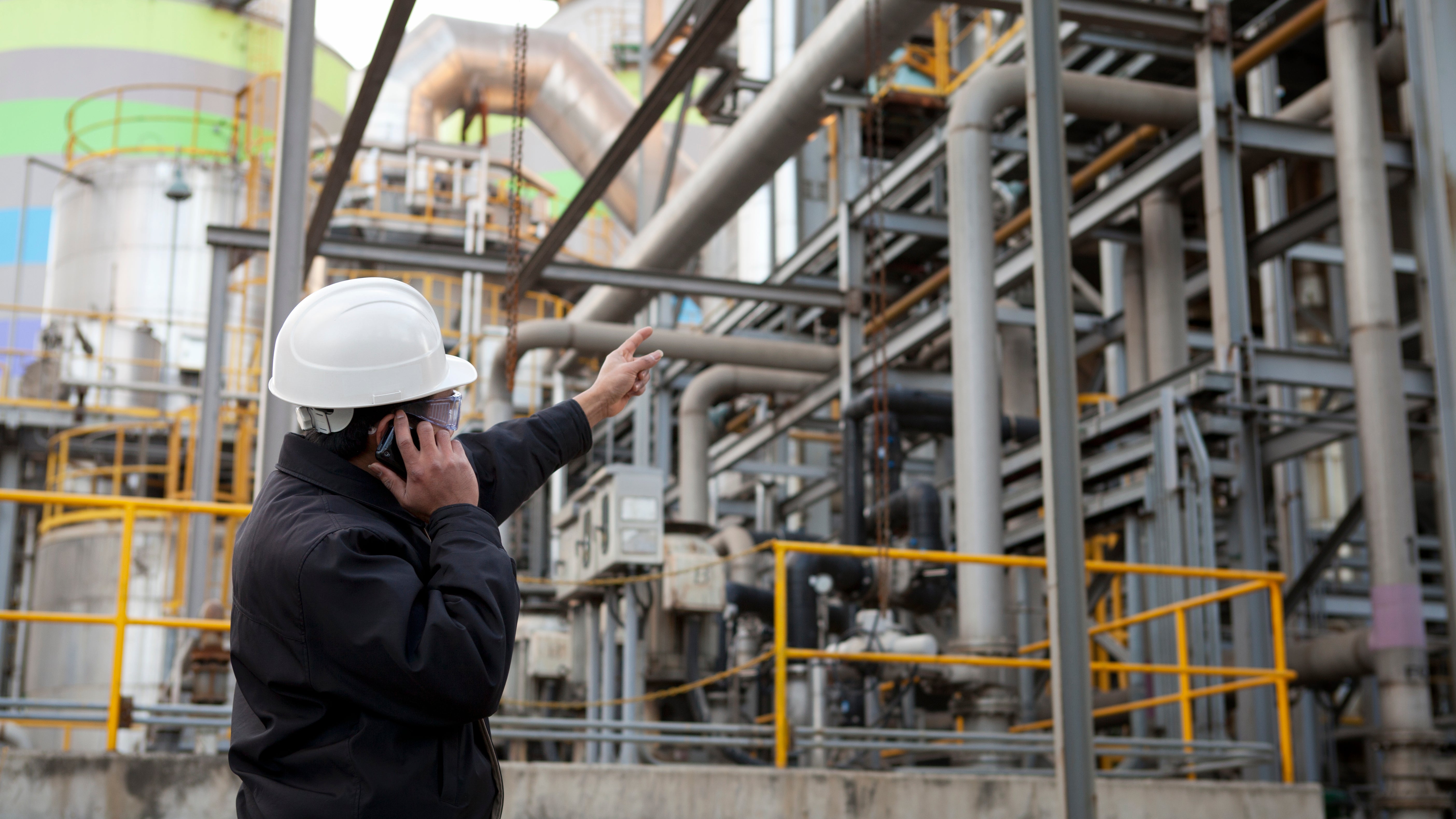 Oil refinery engineer pointing against pipeline