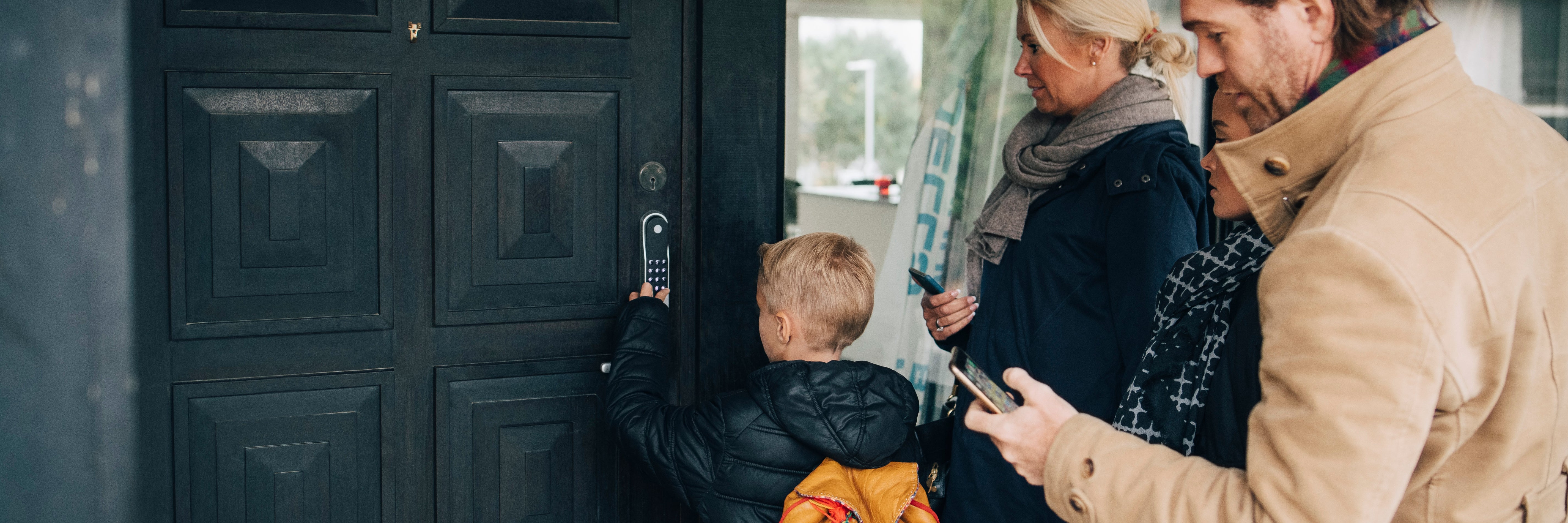 Family using smart lock at front door outside of home