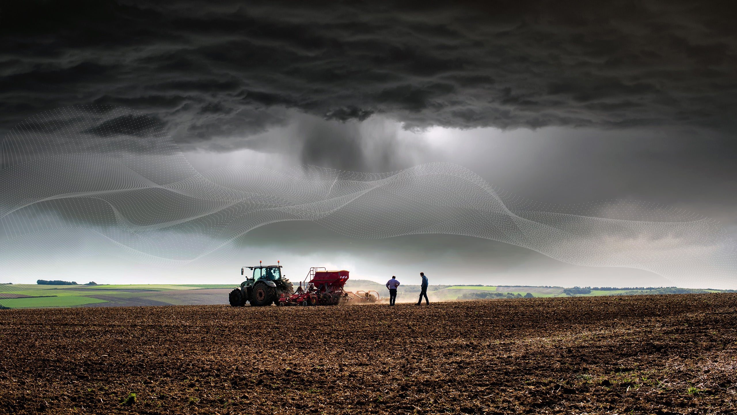 Tractor in farm field under stormy sky