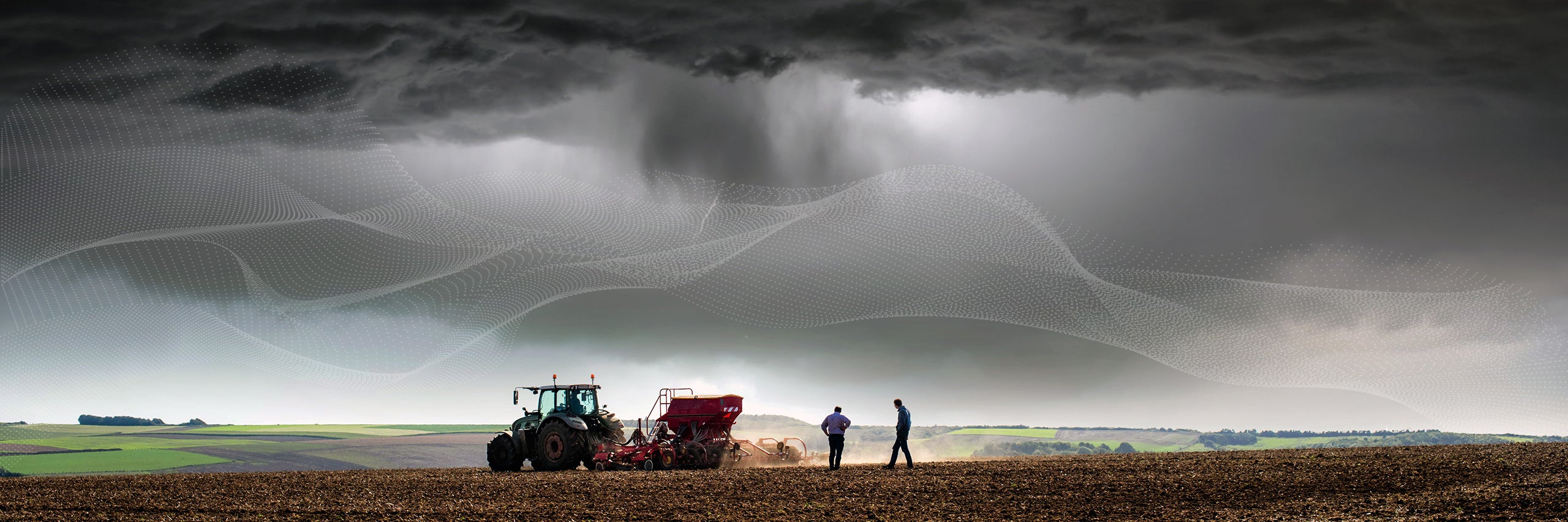 Tractor in farm field under stormy sky