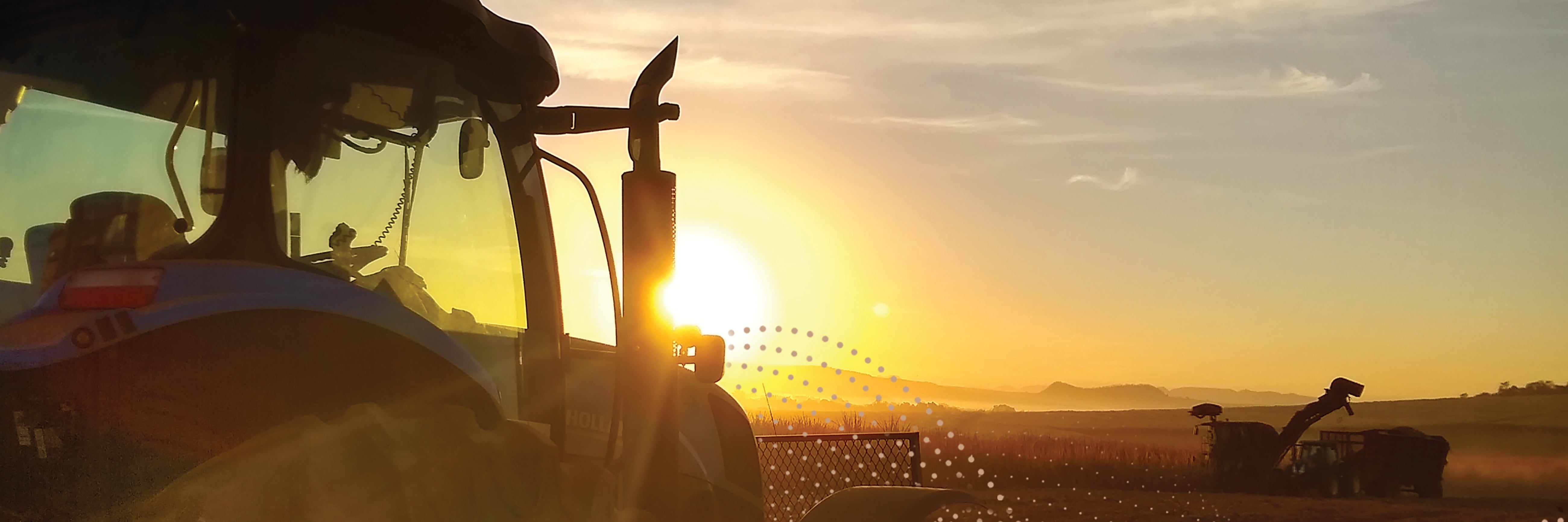 Farm equipment in field at sunset