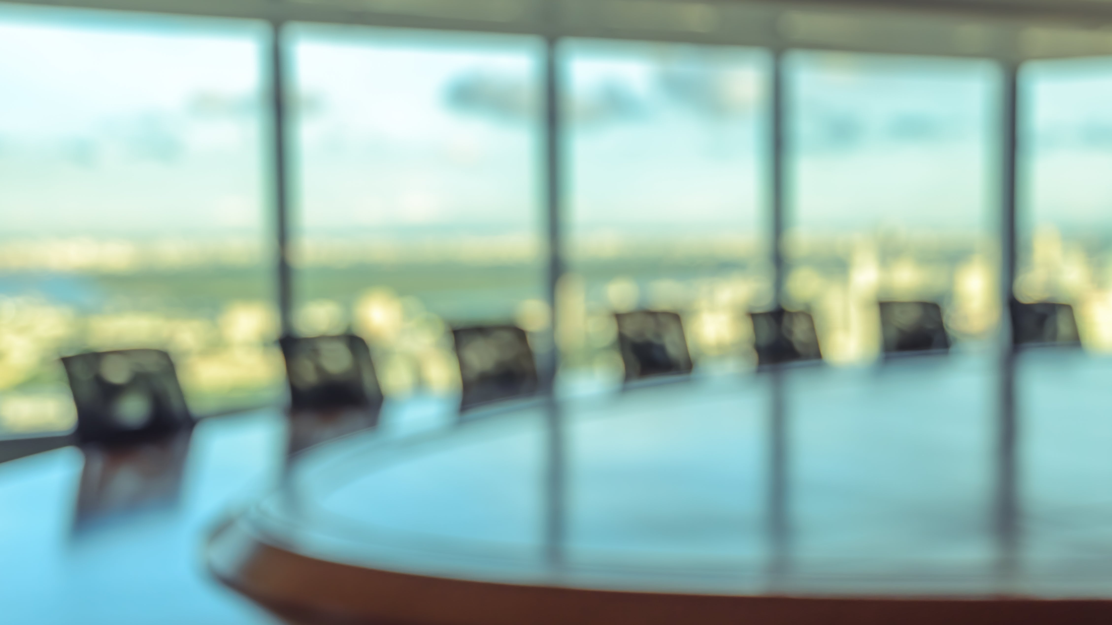 Blurred image of empty boardroom with window cityscape background.
