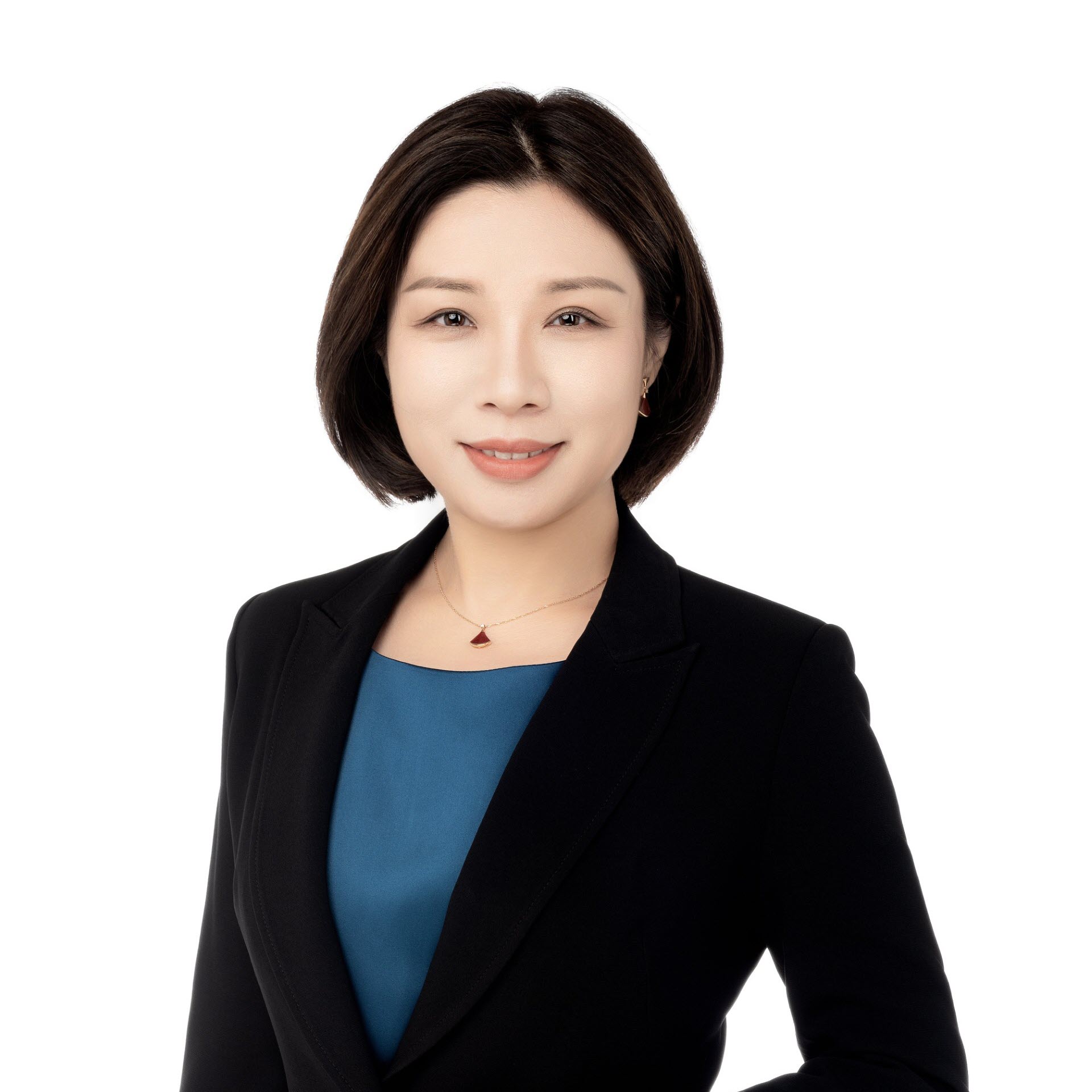 A woman with short hair wearing a black blazer and blue top, smiling against a white background.