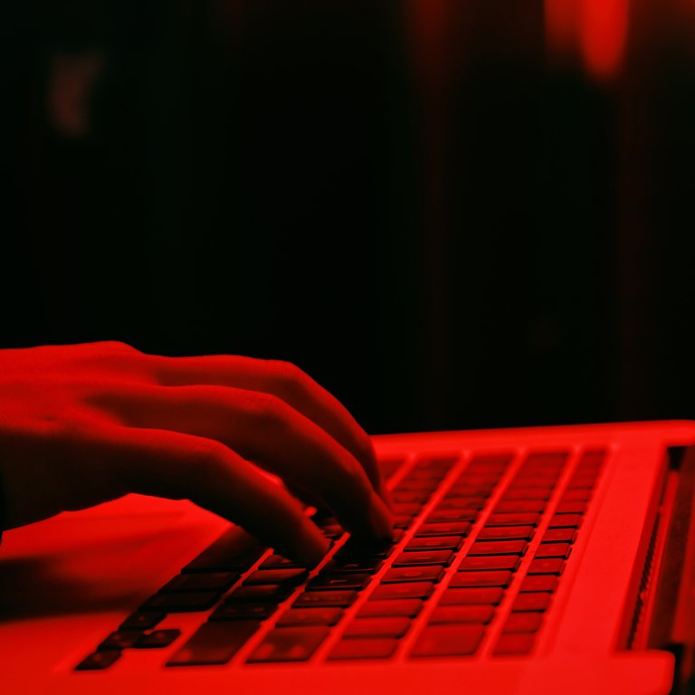 Hands on a laptop keyboard in red light Hands on a laptop keyboard in red light