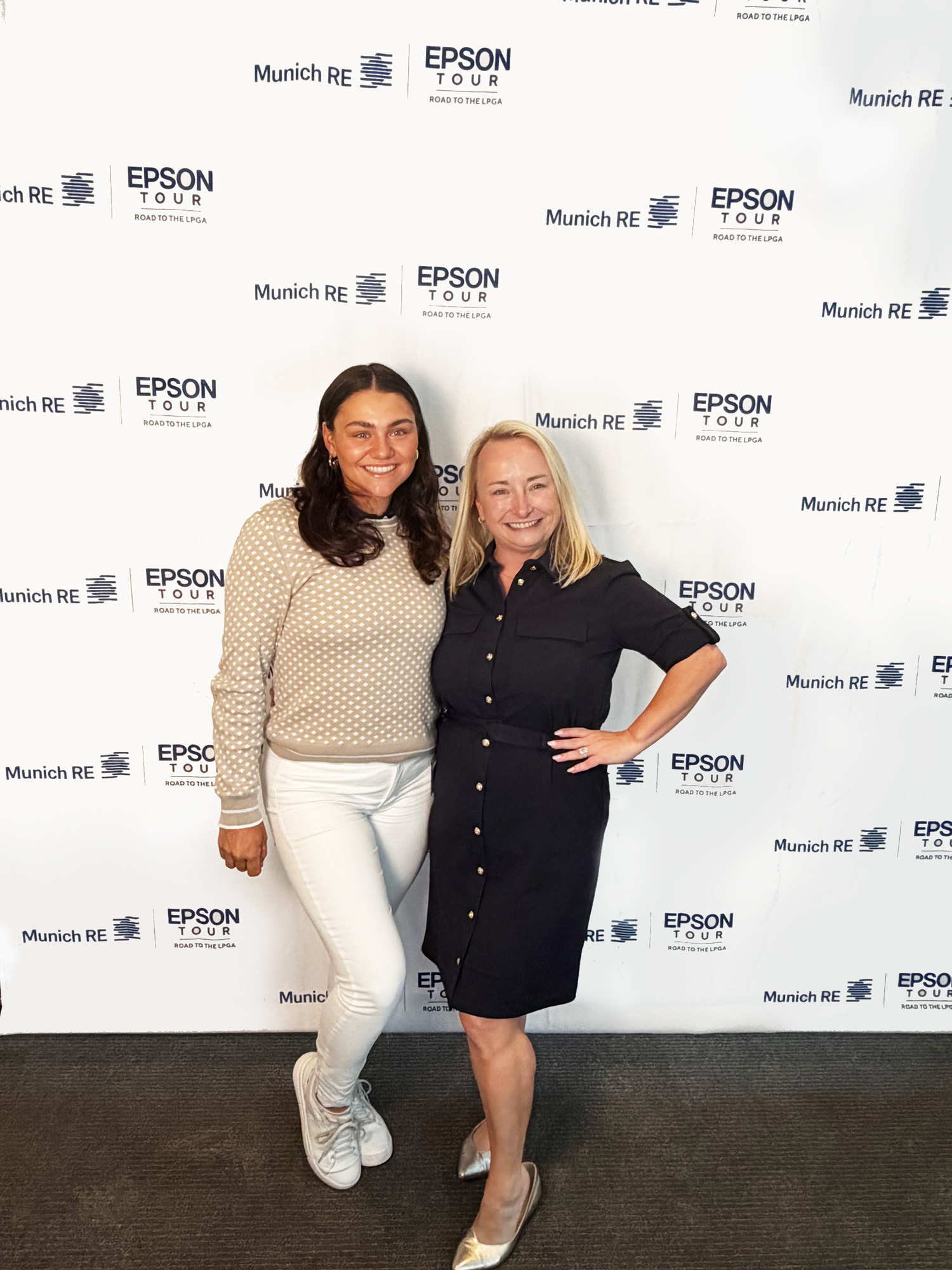 Two women pose together in front of a branded backdrop featuring Epson and Munich Re logos.