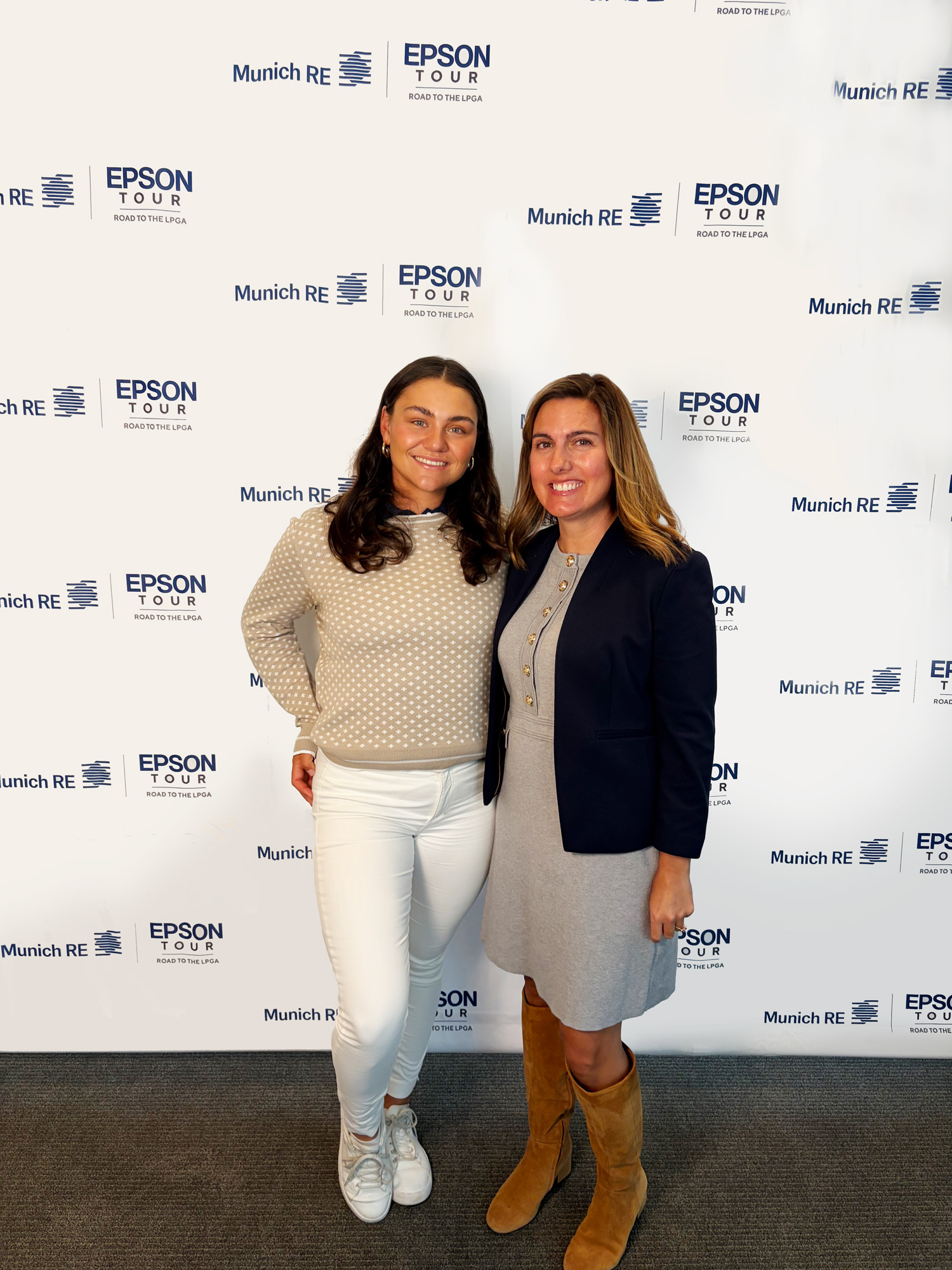 Two women pose together in front of a branded backdrop featuring Epson and Munich RE logos.