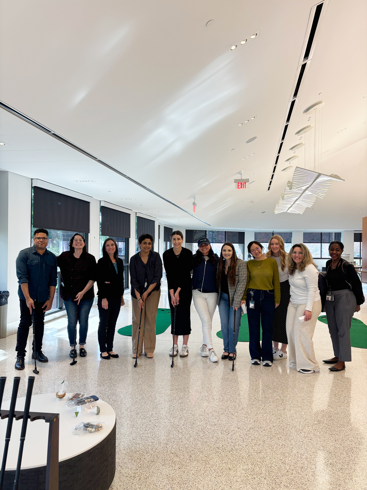 A group of ten people stands together indoors, some holding canes, with a modern, bright space in the background.