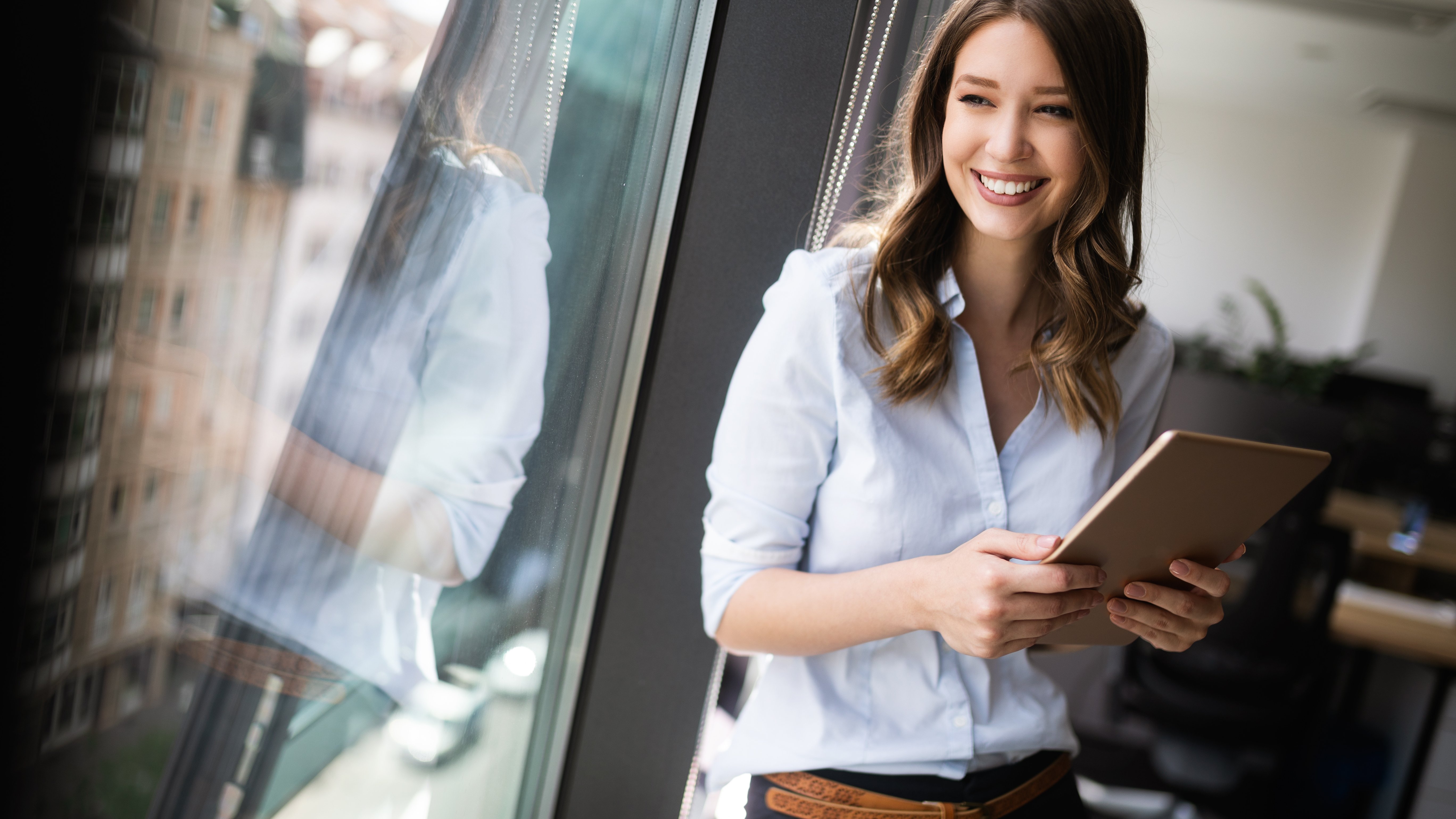 Contact us Young businesswoman using a digital tablet while standing in front of windows