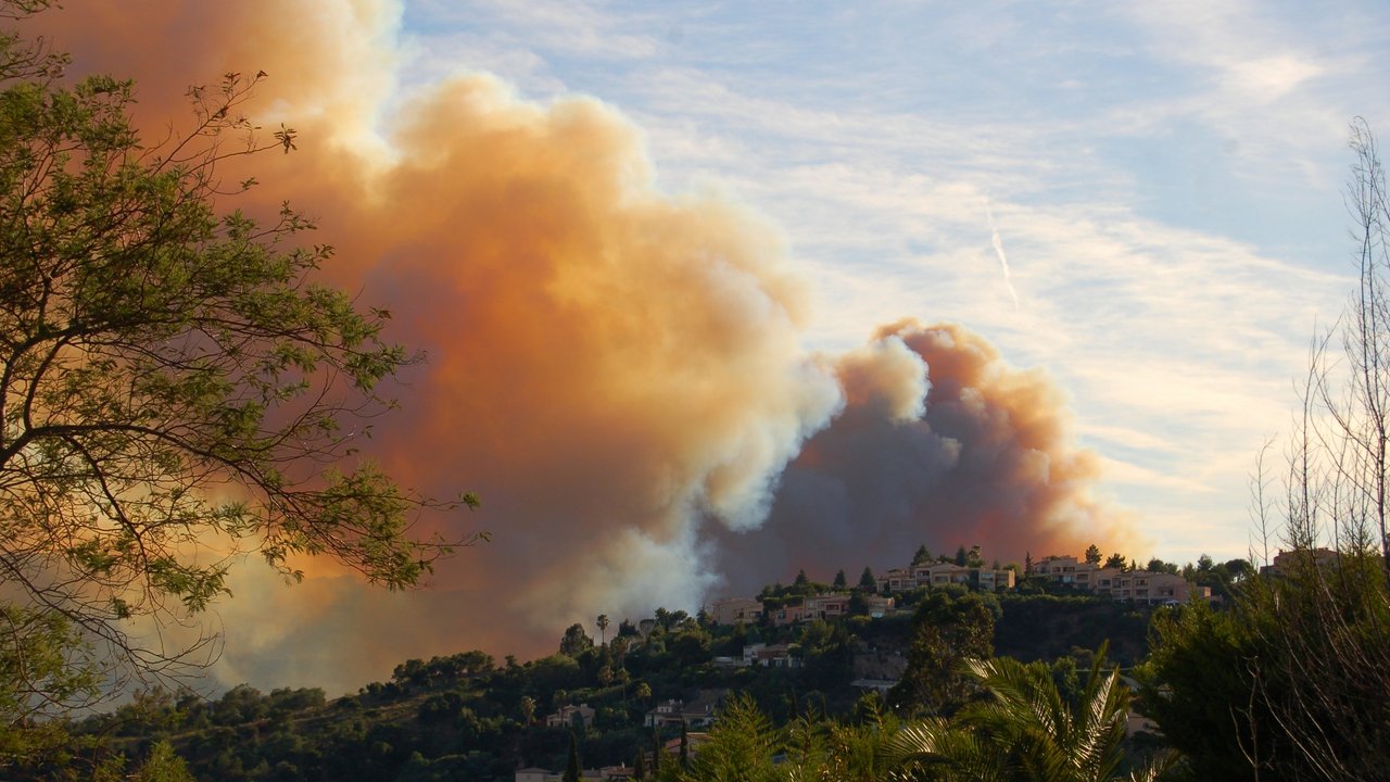 Image description:  Forest and bush fires raging behind a hill in the south of France. Giant smoke clouds are going up into the sky next to the living area of the french south.