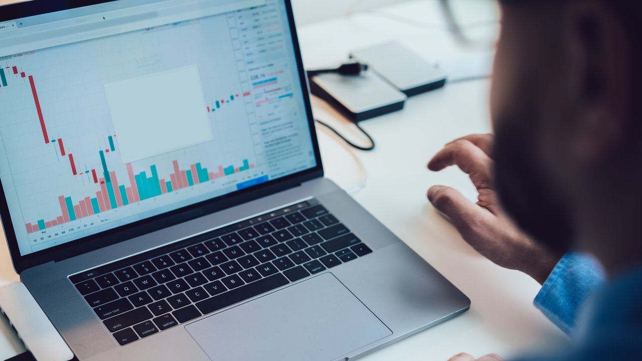 Crop anonymous male entrepreneur in blue shirt analyzing graph on computer while working in cryptocurrency trading company at modern office