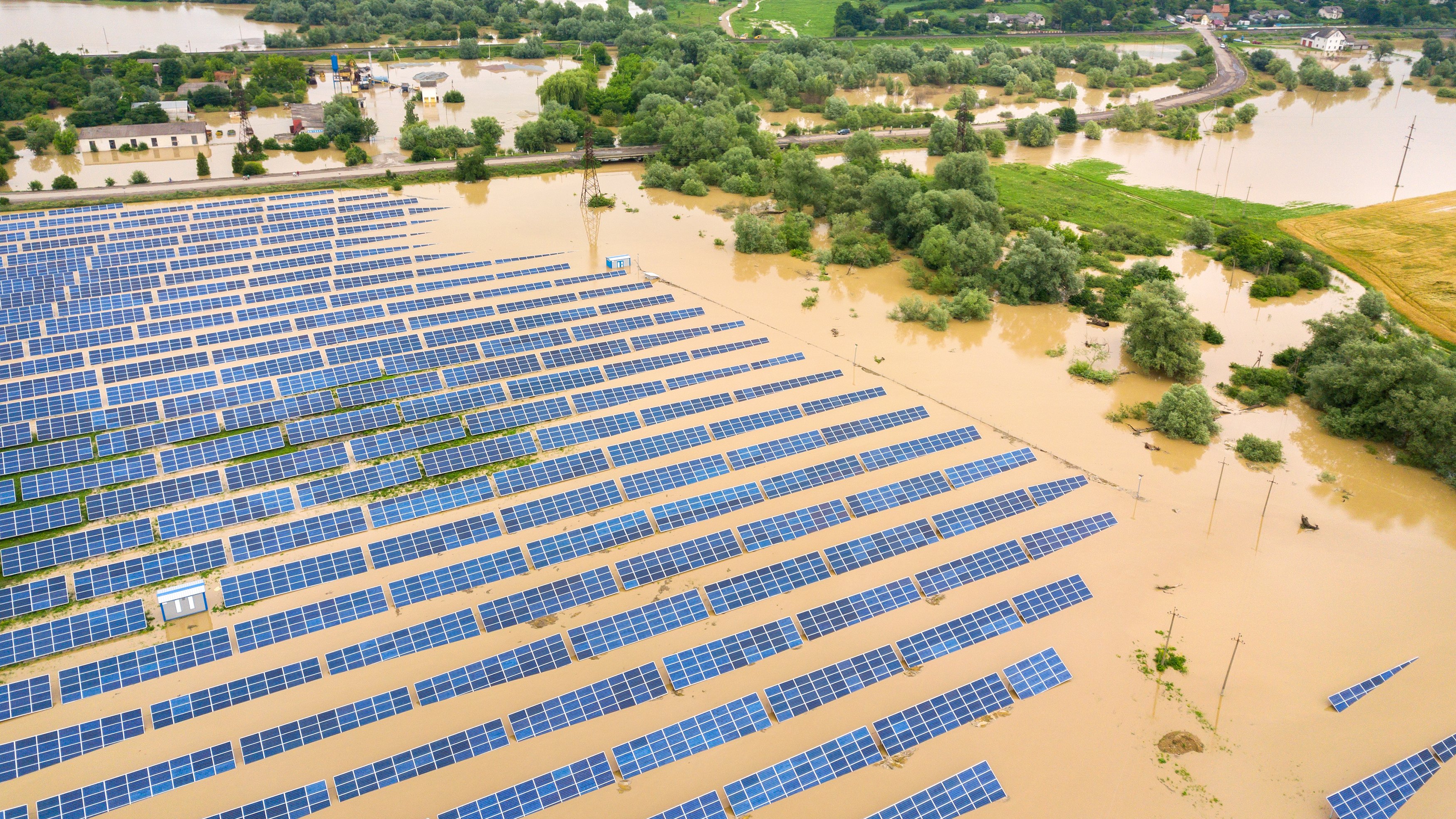 Aerial view of flooded solar power station with dirty river water in rain season.