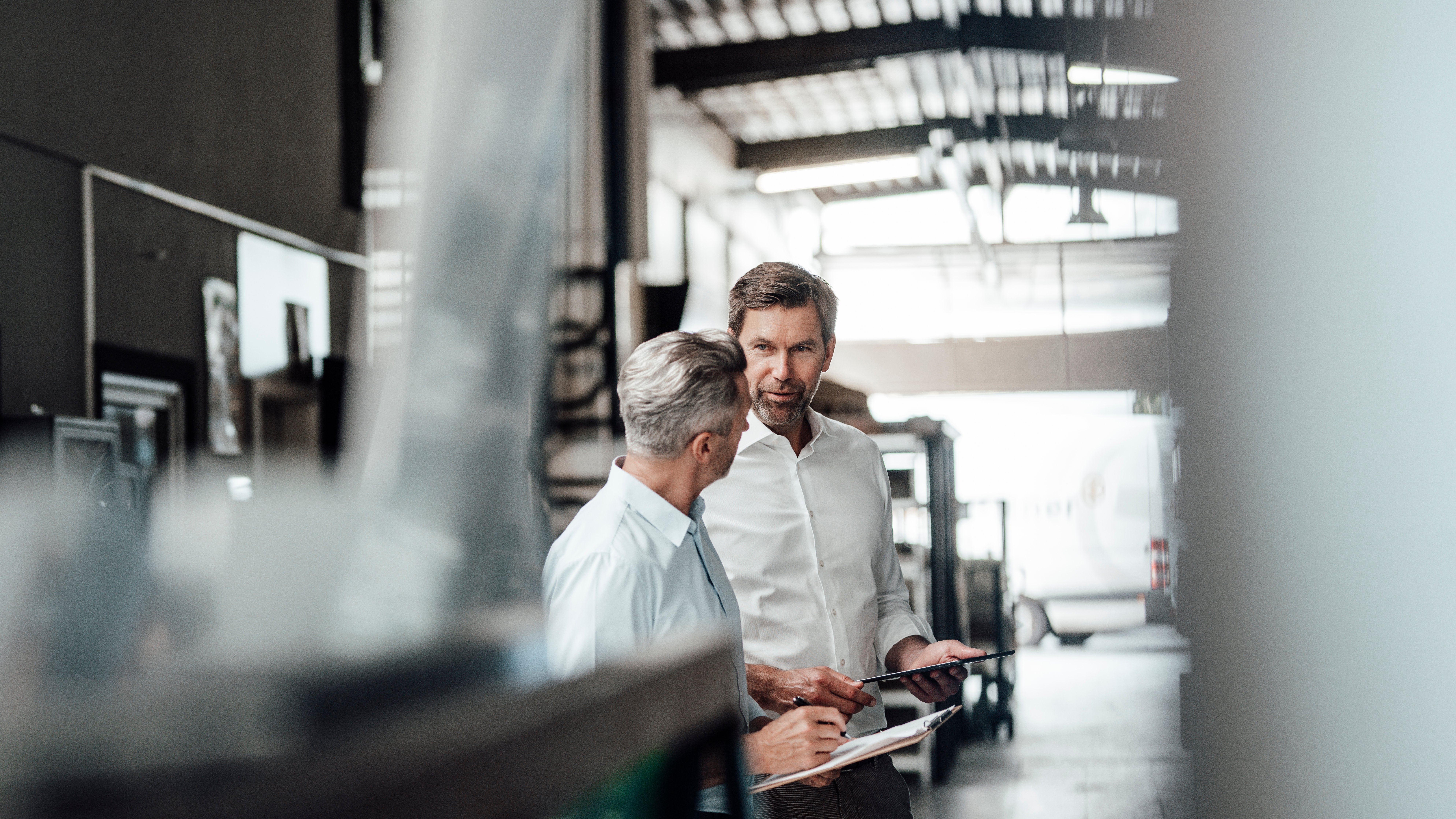 Entrepreneur holding digital tablet while having discussion with colleague at factory
