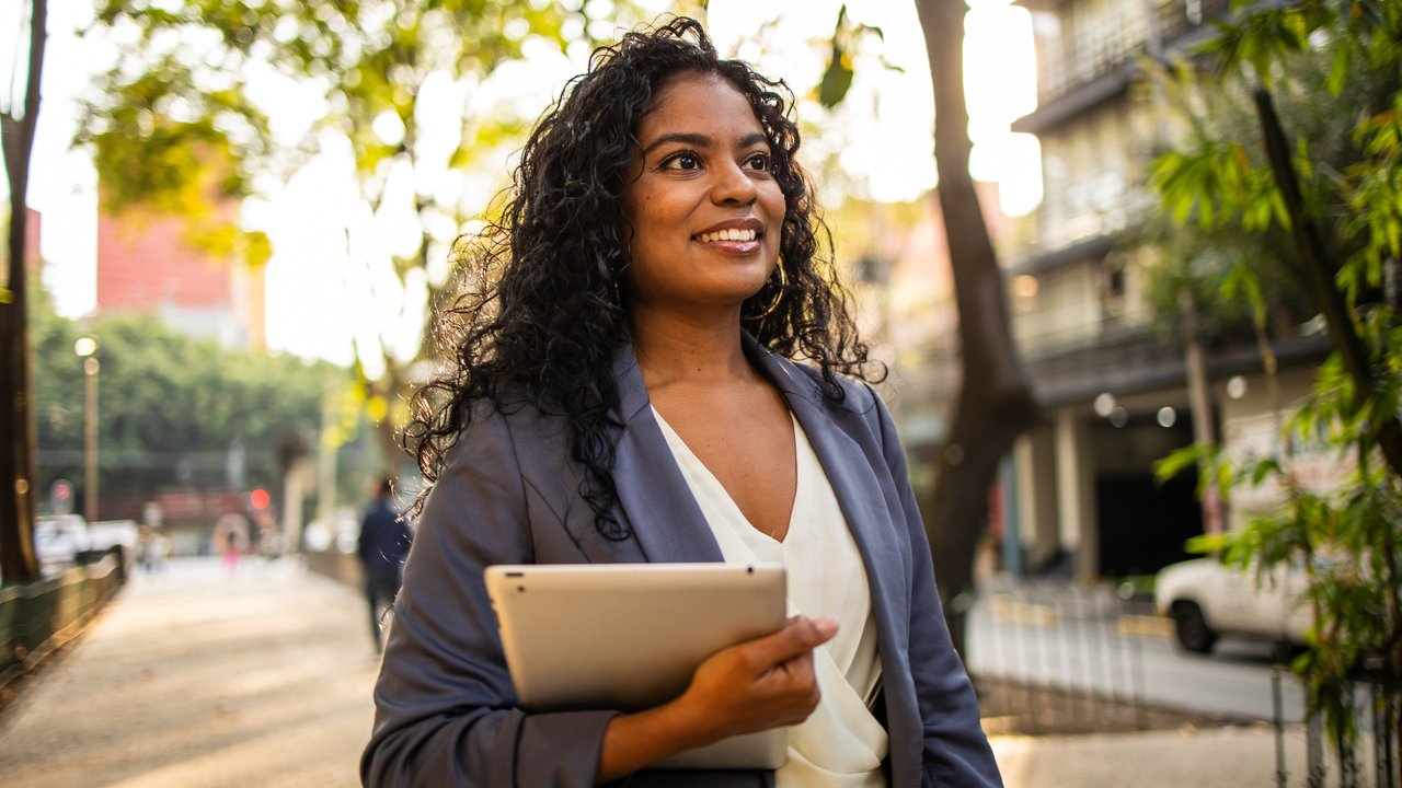 Businesswoman holding digital tablet and walking in the city