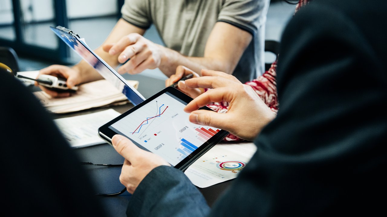 Business team holding a meeting and looking at third-party data on digital tablets for life insurance underwriting