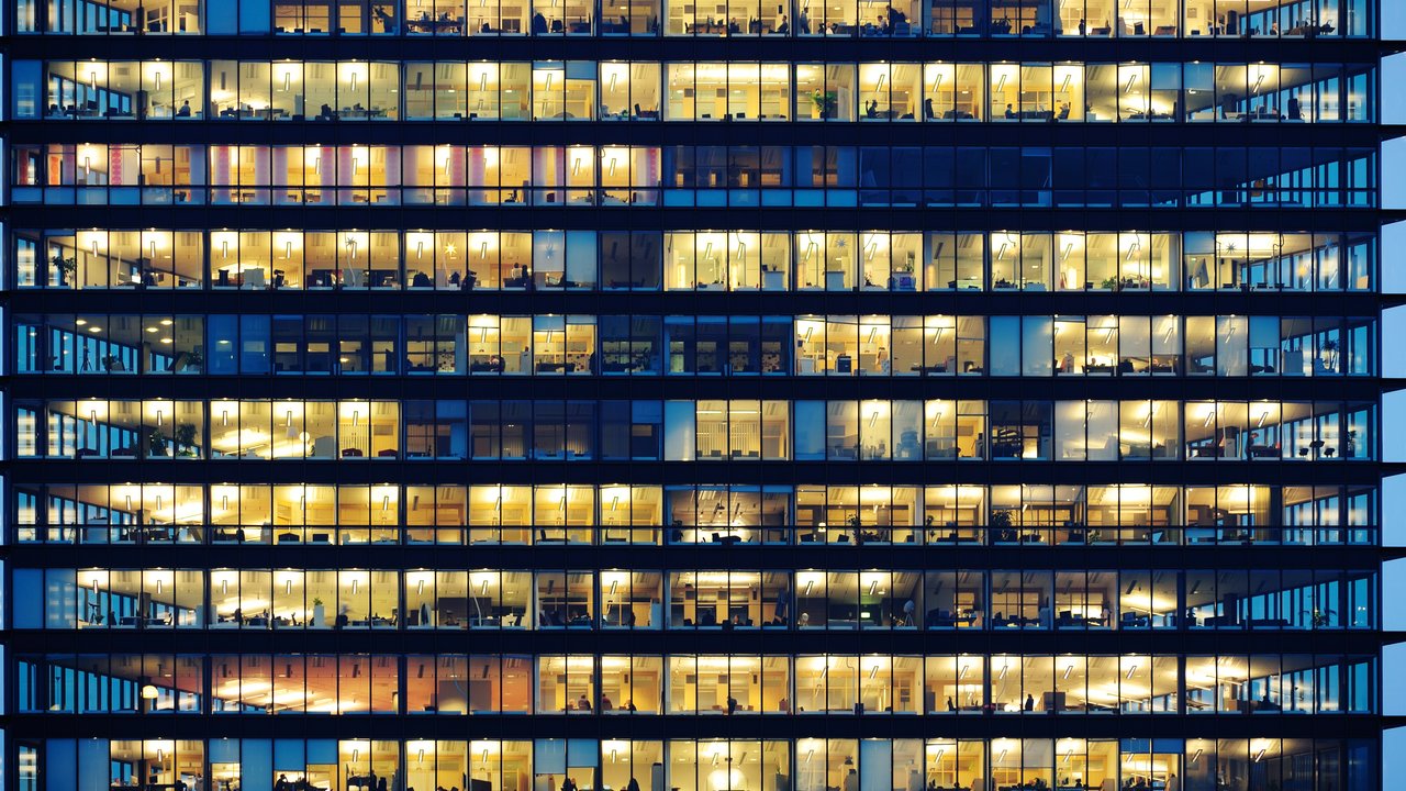 A view of an office building with lots of lights and people working