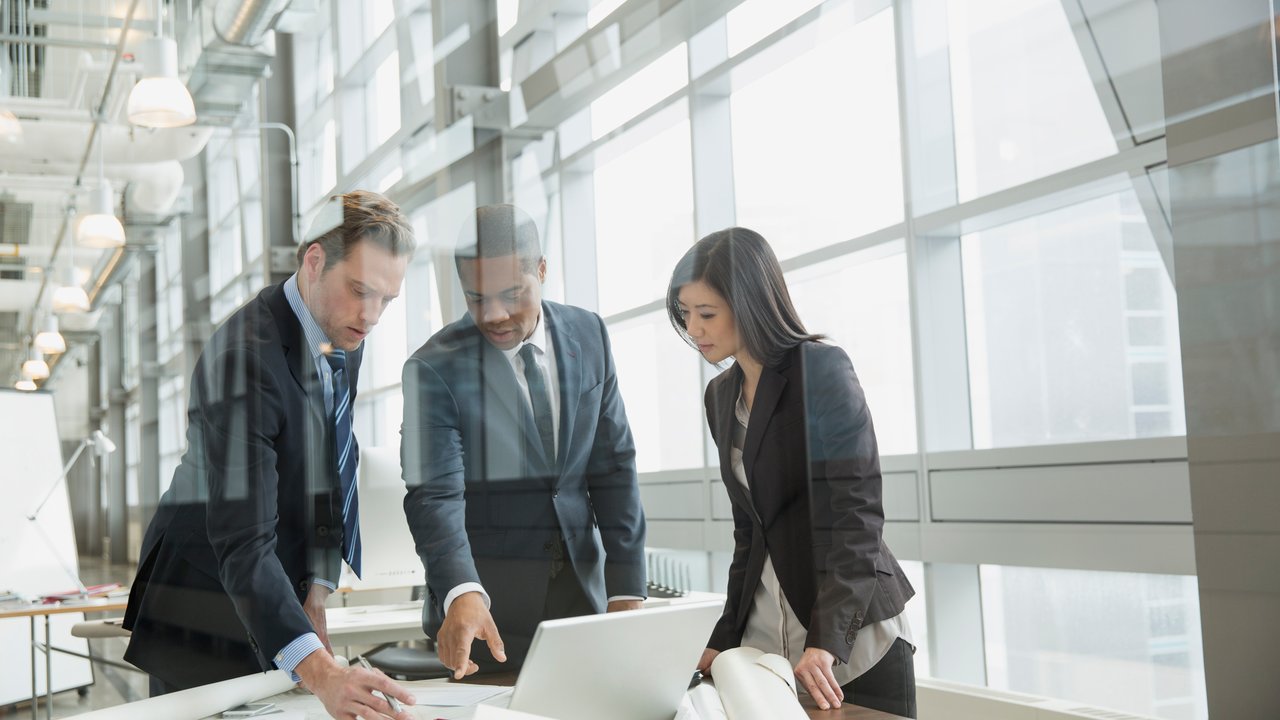 Business people reviewing blueprints at desk