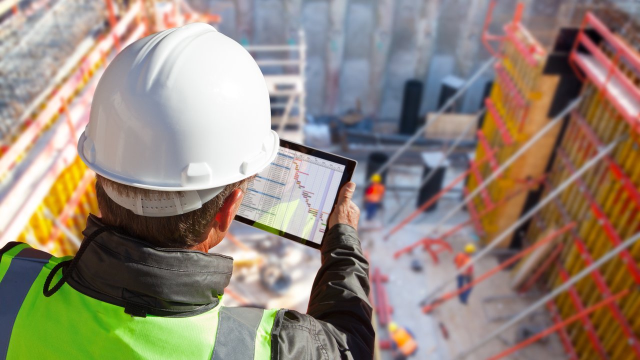 civil engineer or architect on construction site checking schedule with tablet computer