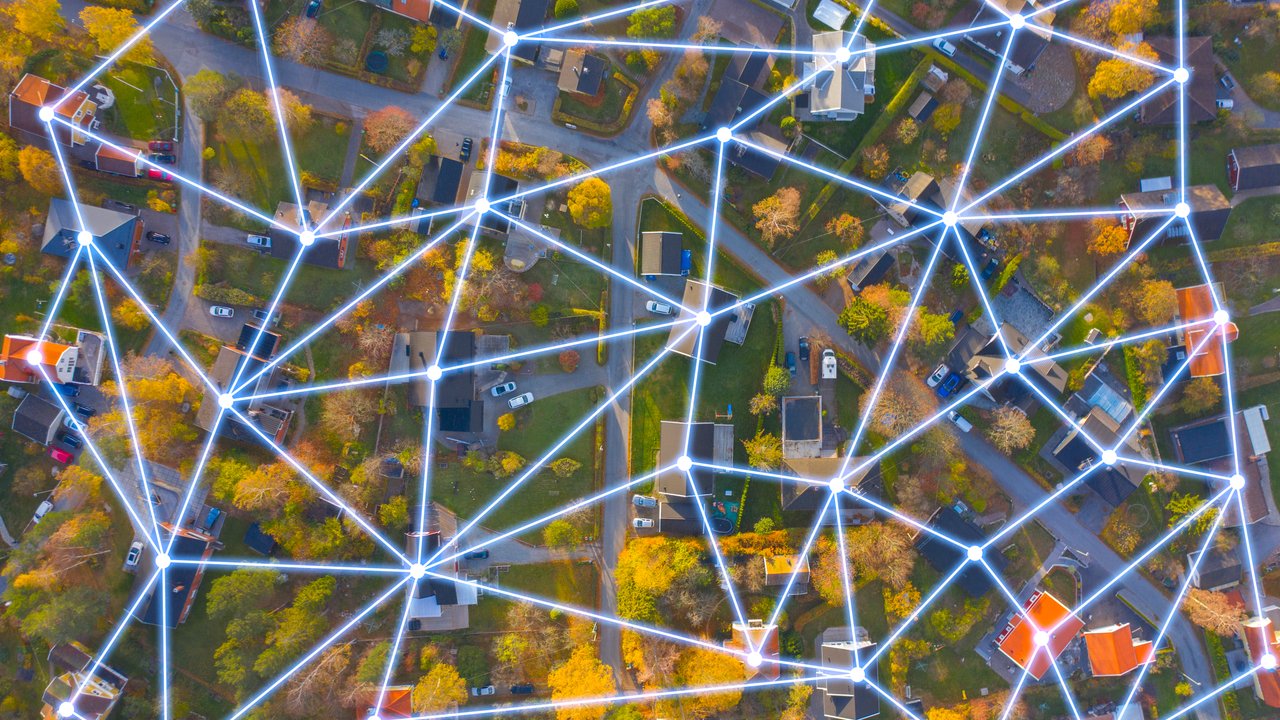 Building a stronger future through prevention, partnerships, and preparedness Aerial view of a neighborhood with houses and trees, overlaid with a network of glowing lines and nodes.