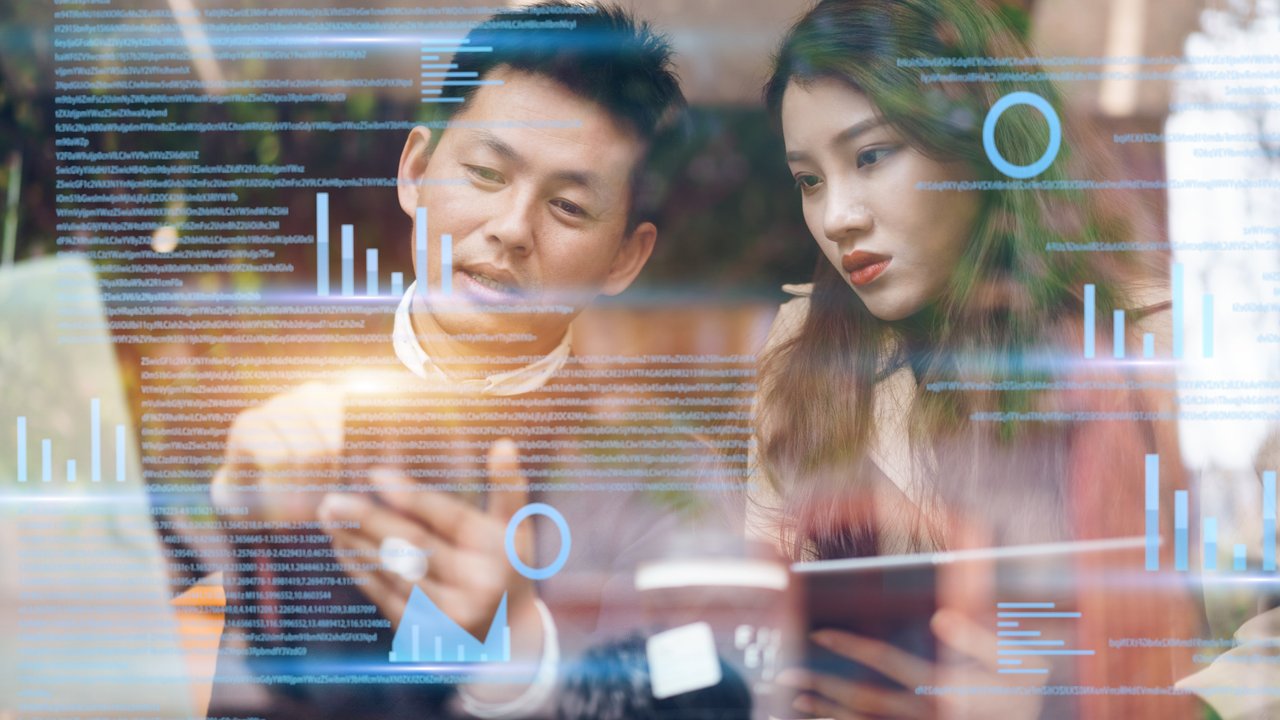 man and woman looking at concepts of data floating outside of a laptop
