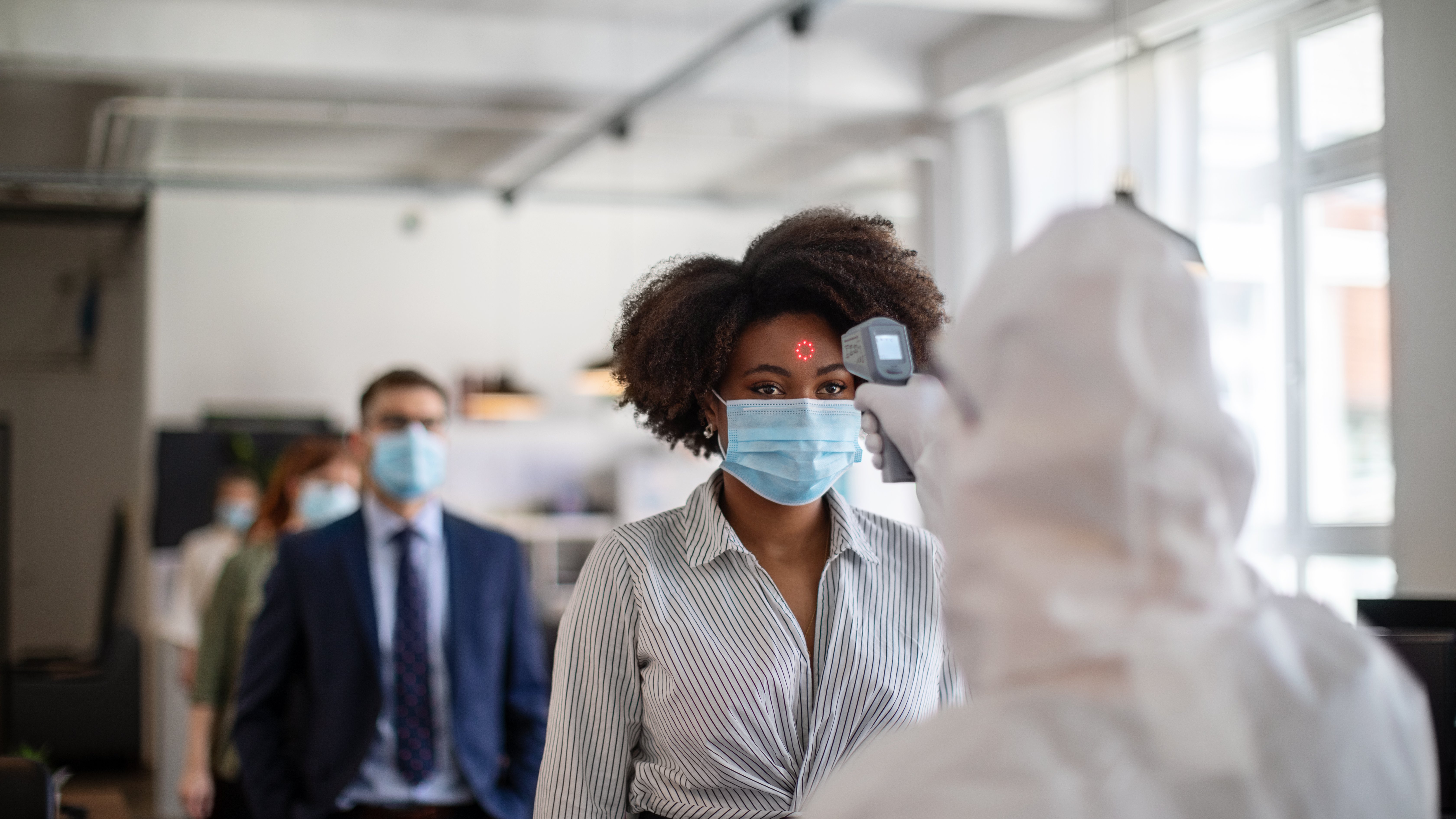 La COVID longue à la 5e année : quelques progrès, encore beaucoup de questions Doctor in personal protective equipment vaccinating a patient for COVID19