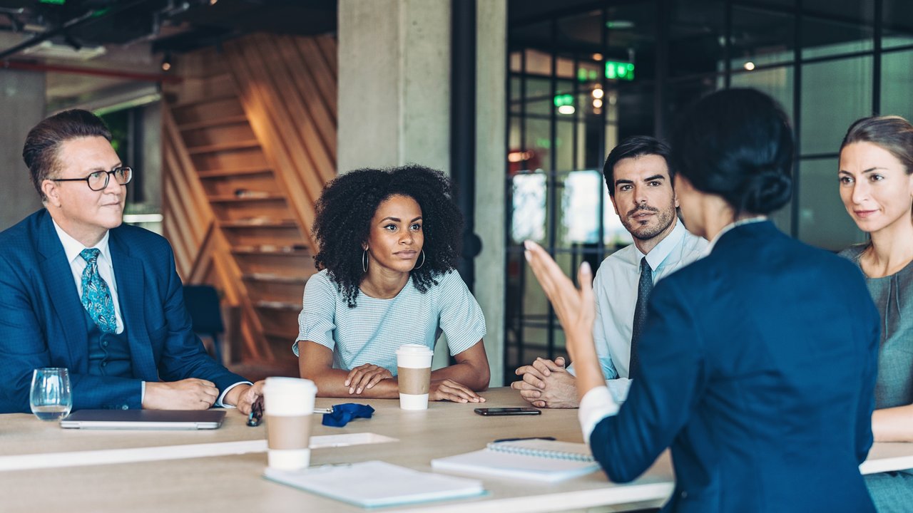 A Group of businesspeople sitting in meeting and listening to female colleague