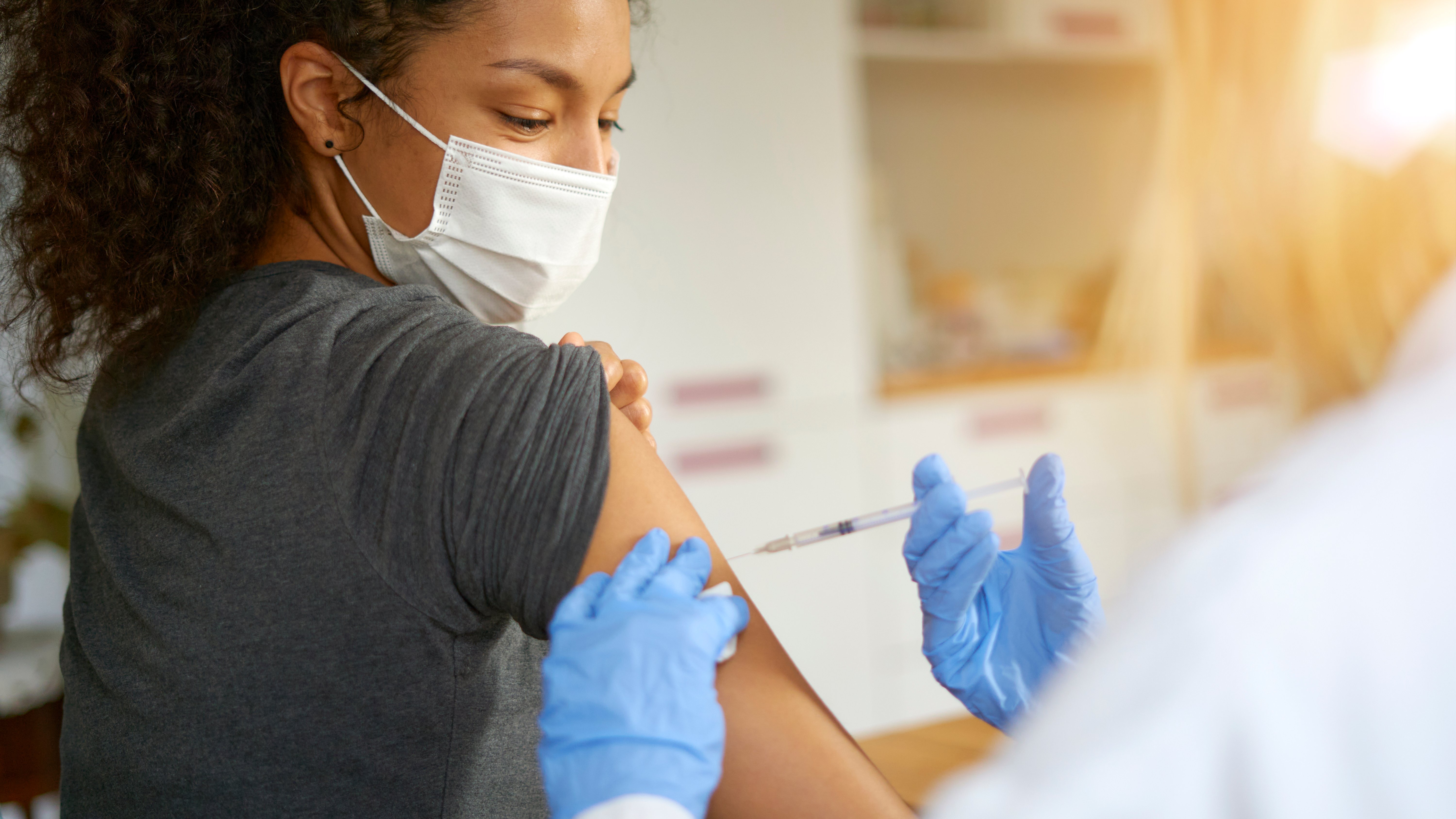 The long-term complications of COVID-19 infection Close-up portrait of a beautiful young woman wearing a mask getting vaccinated.
