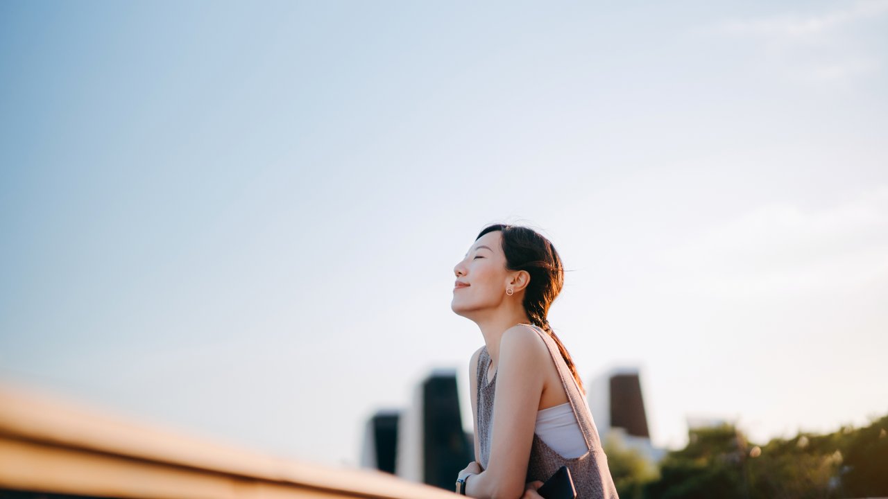 Woman in front of a city skyline looking up to the sky
