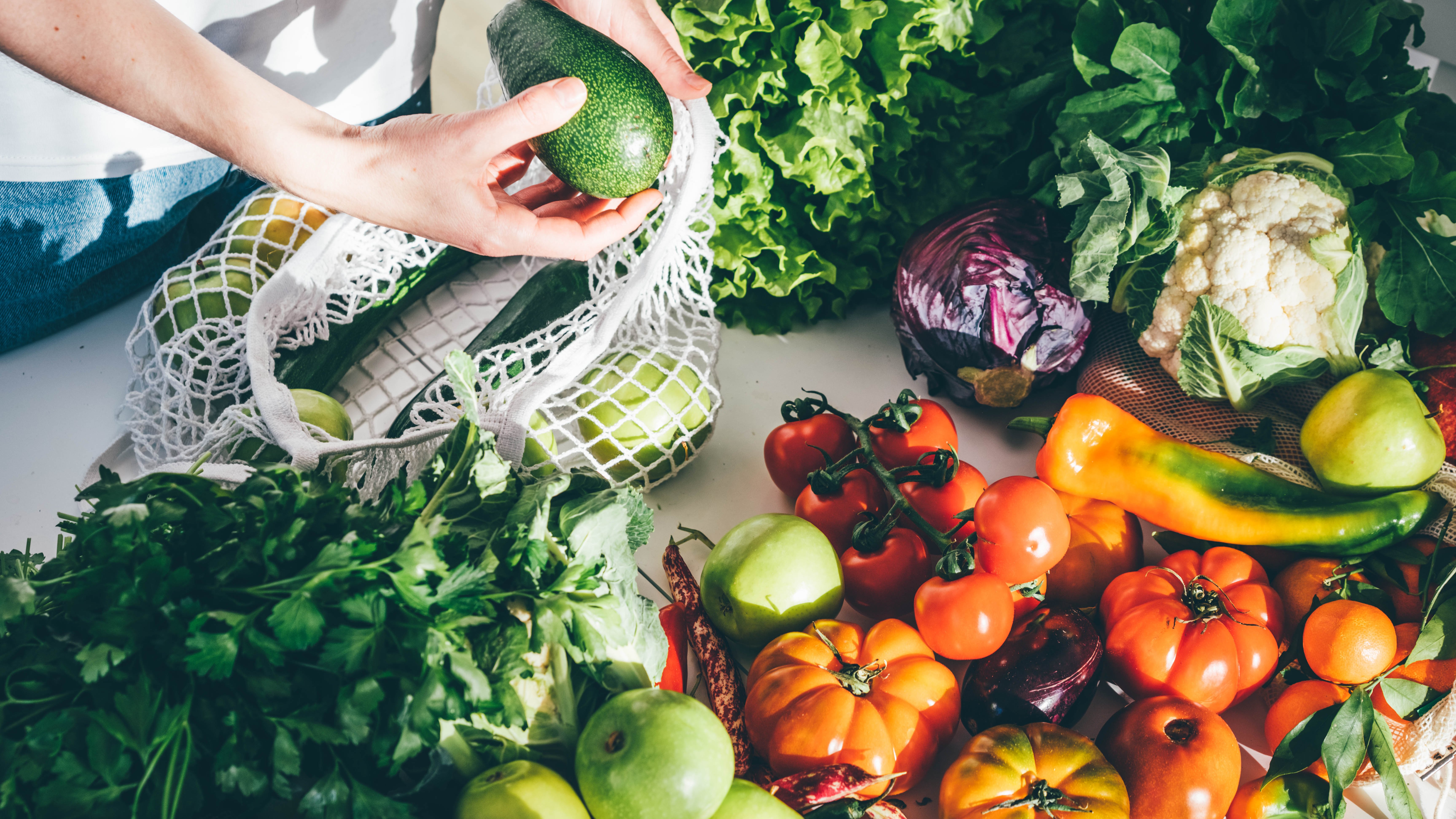 Woman putting fresh organic vegetables on a kitchen table