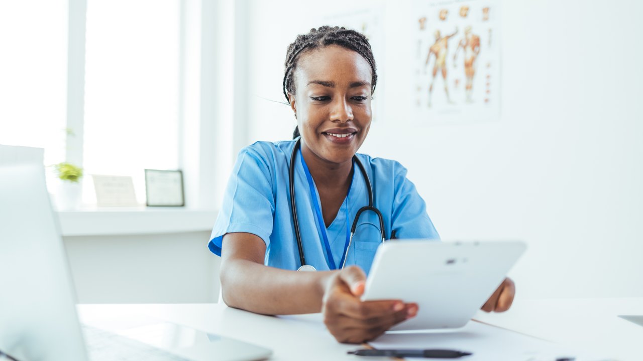 Female nurse or doctor smiles while holding digital tablet