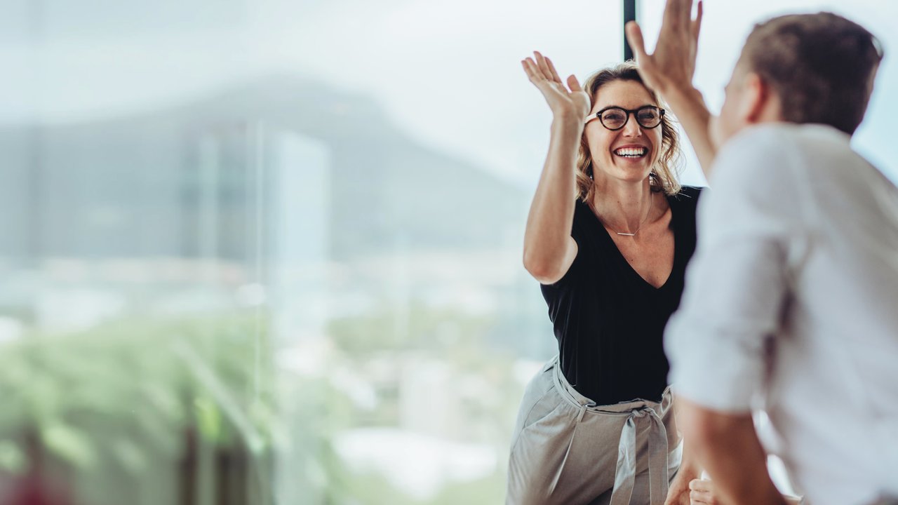 Businesswoman giving a high five to male colleague in meeting