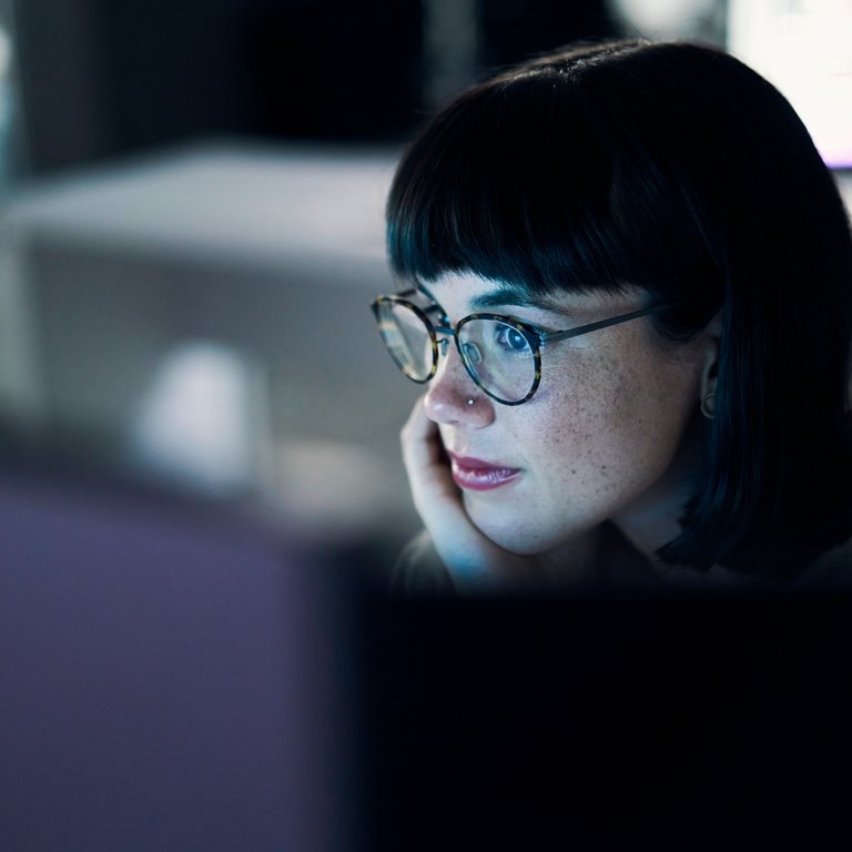 Business woman, computer seo and web design of young worker thinking with blue light and glasses. Digital code, female face and reading of a employee at night planning with online ux and media data