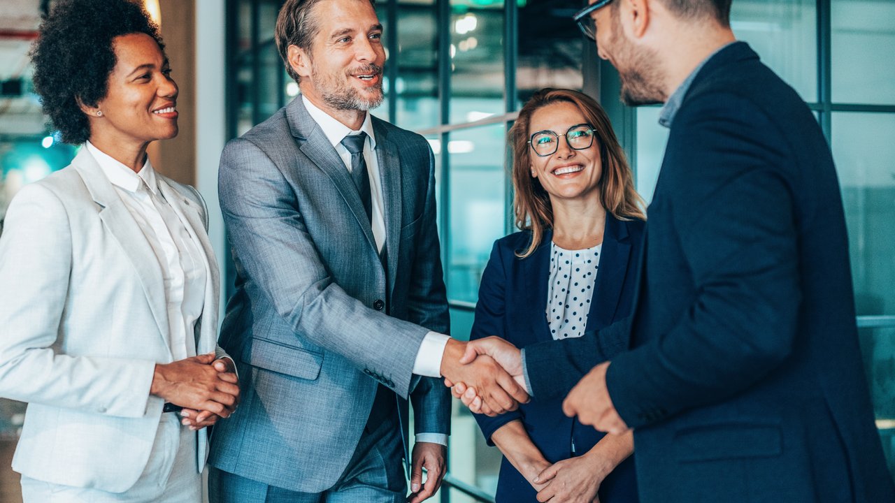 Group of business persons shaking hands in the office after closing a partnership deal Group of business persons shaking hands in the office after closing a partnership deal