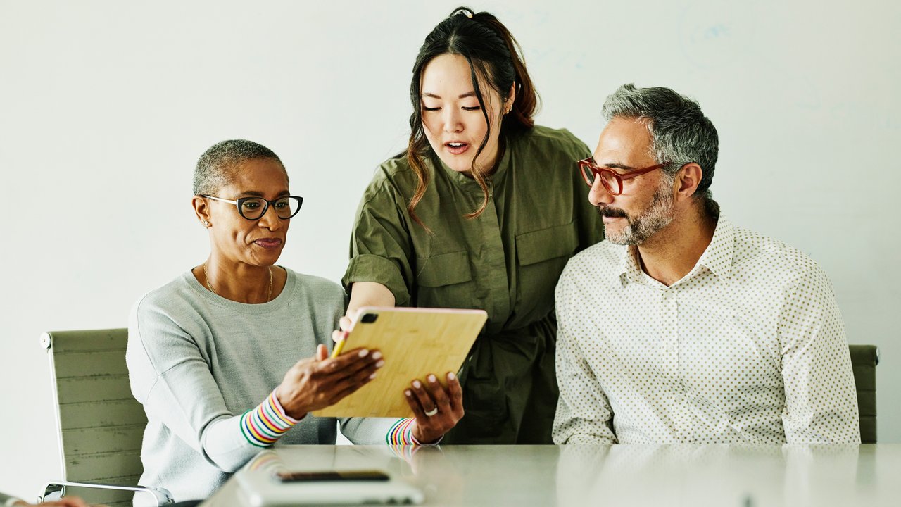 Three business colleagues discussing accelerated underwriting in Canada on a digital tablet