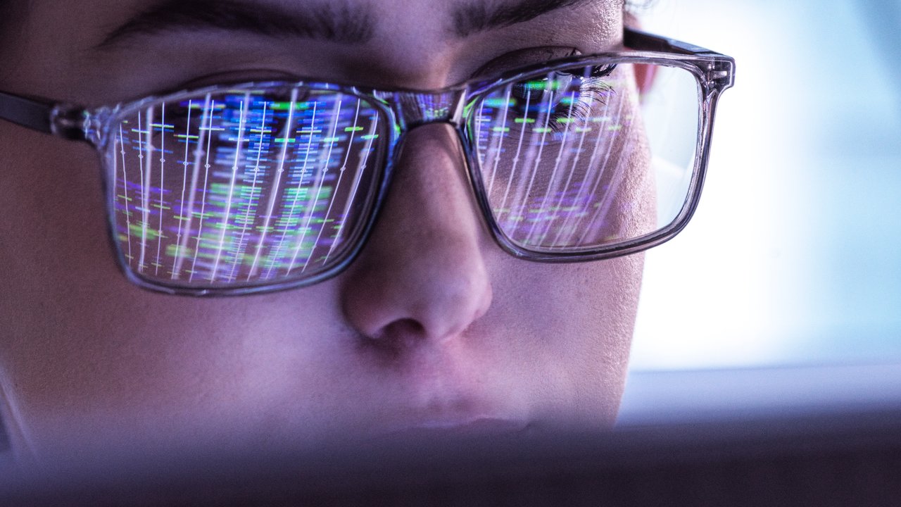 Scientist wearing eyeglasses and analyzing DNA data on computer