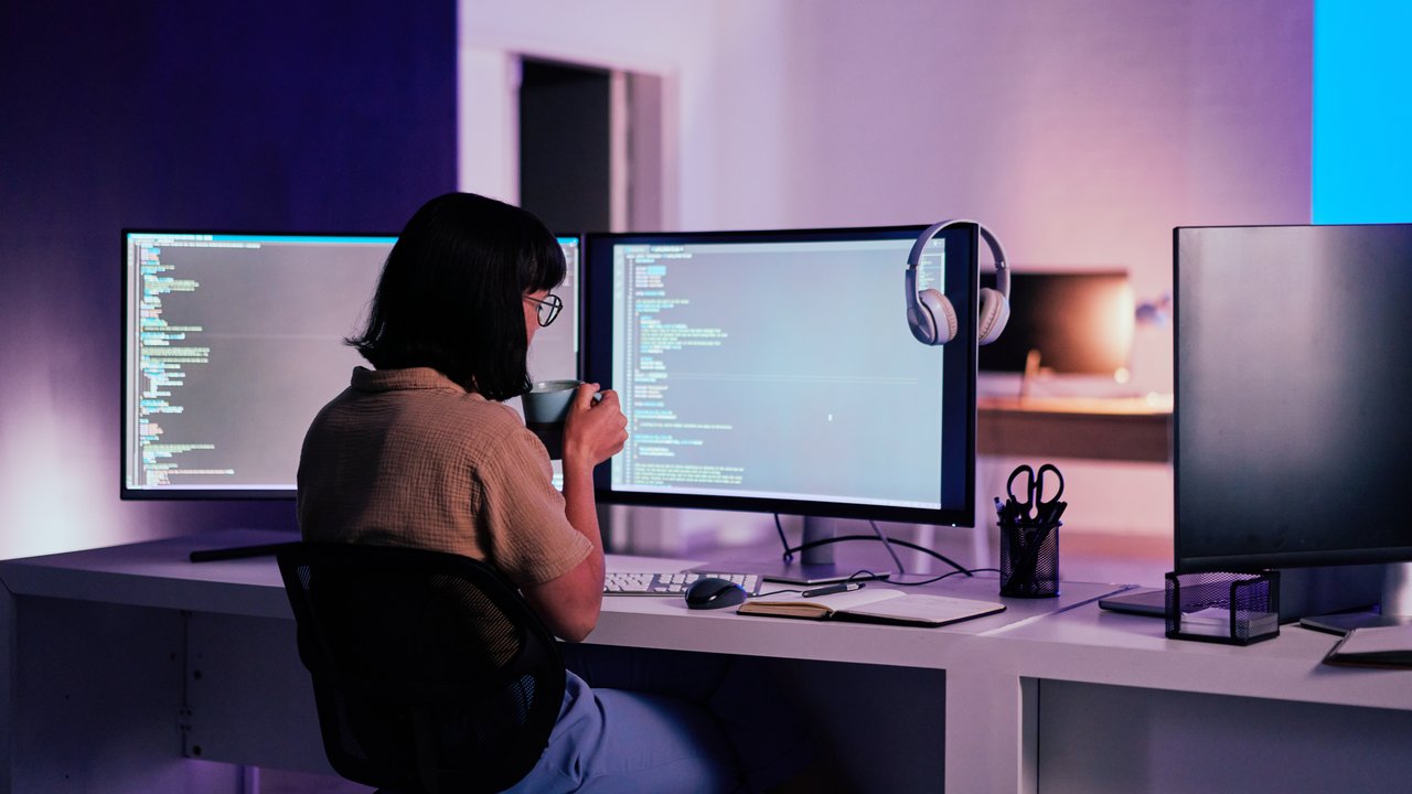 Female programmer sitting at desk with multiple computer screens looking into innovative techniques such as multi-party computation