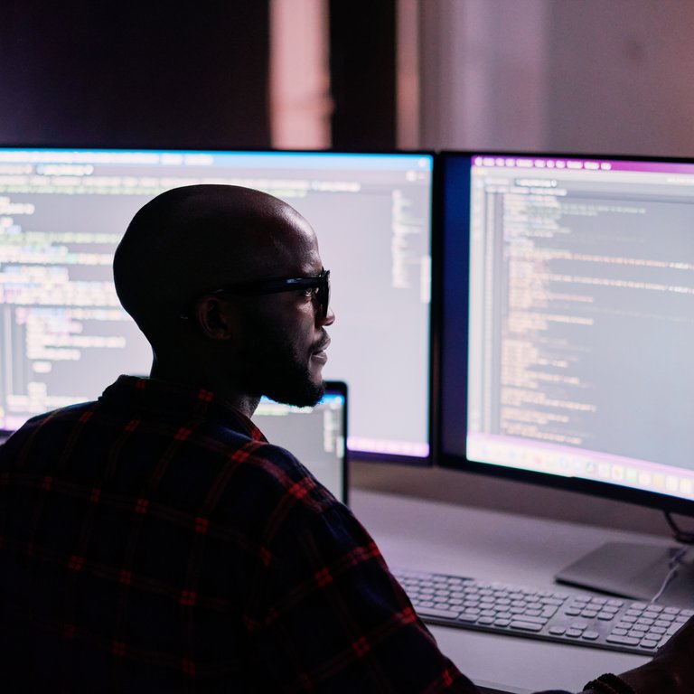 Cyber security, black man and code reflection in eyewear, hacking and software update in office. African American male employee, programmer or IT specialist with glasses, focus and cloud computing