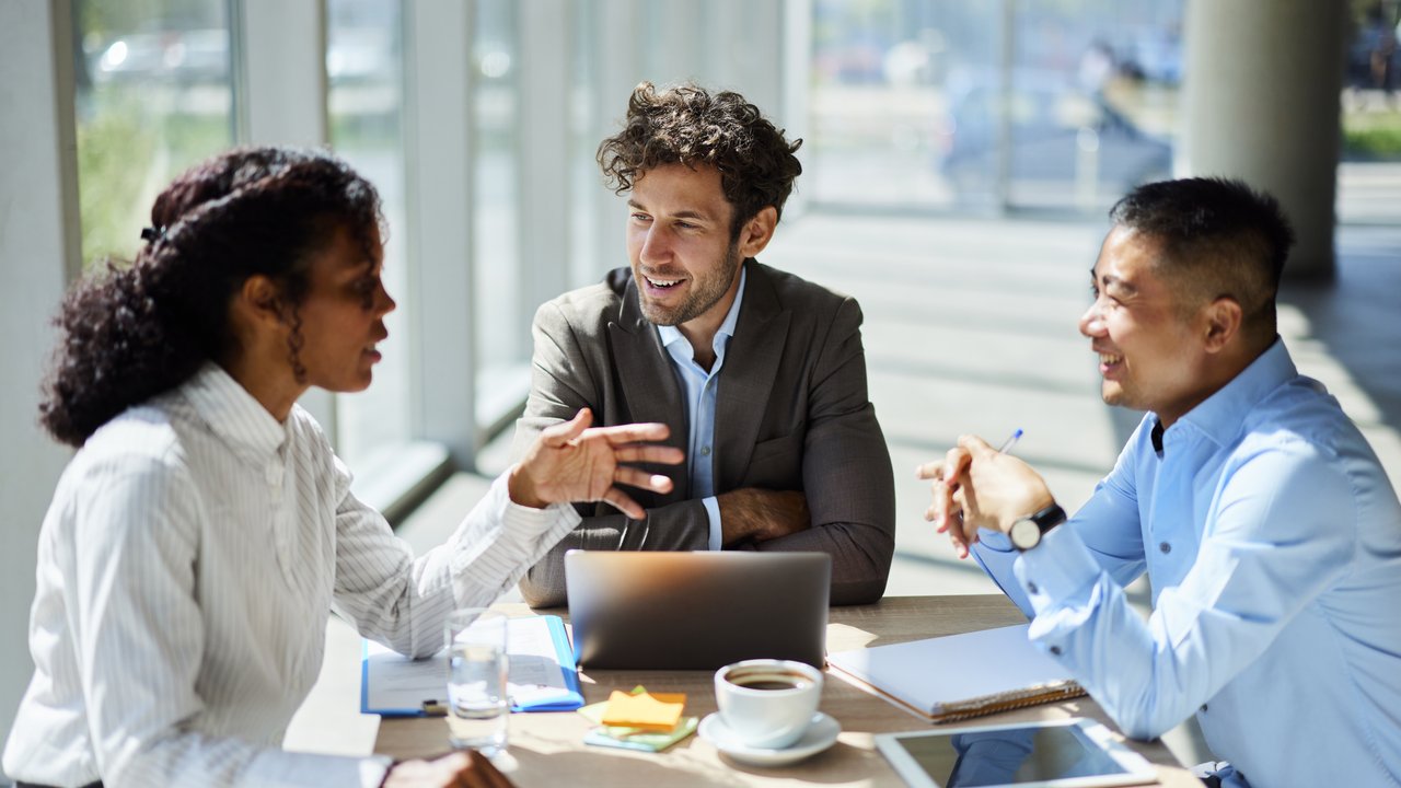 Three diverse business colleagues in a discussion about the EHR Retro Study on fully underwritten cases