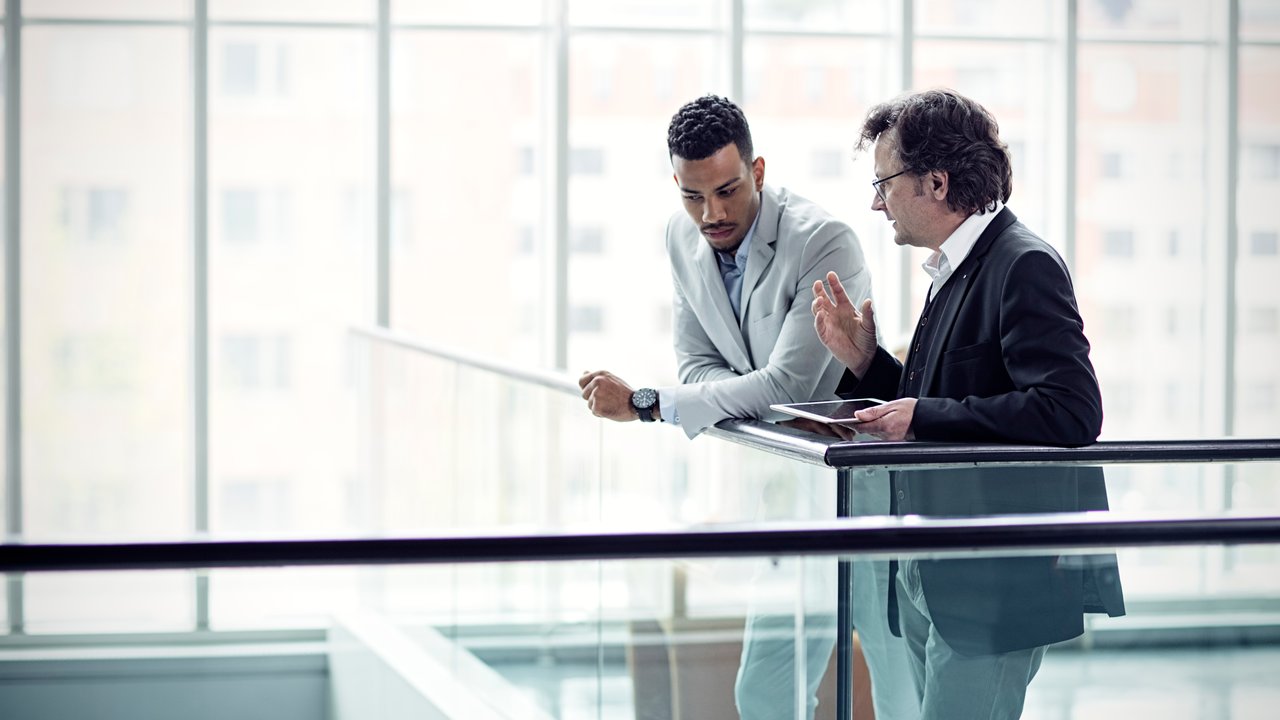 Two businessmen in a hallway discussing