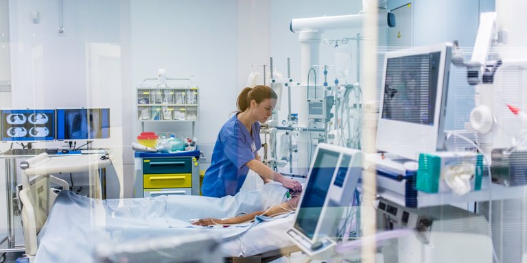 Nurse checking on patient in hospital bed