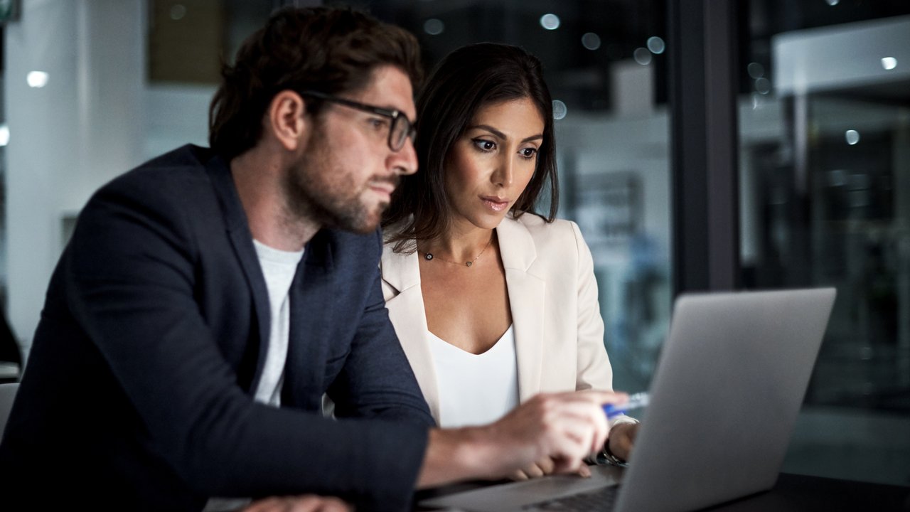 Shot of colleagues using a laptop together at work