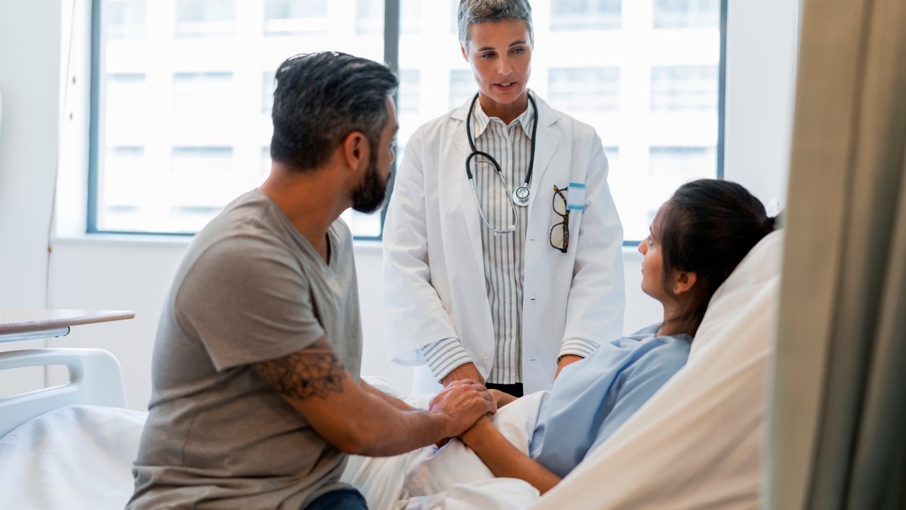 Doctor at hospital ward talking to a couple about their critical illness insurance 