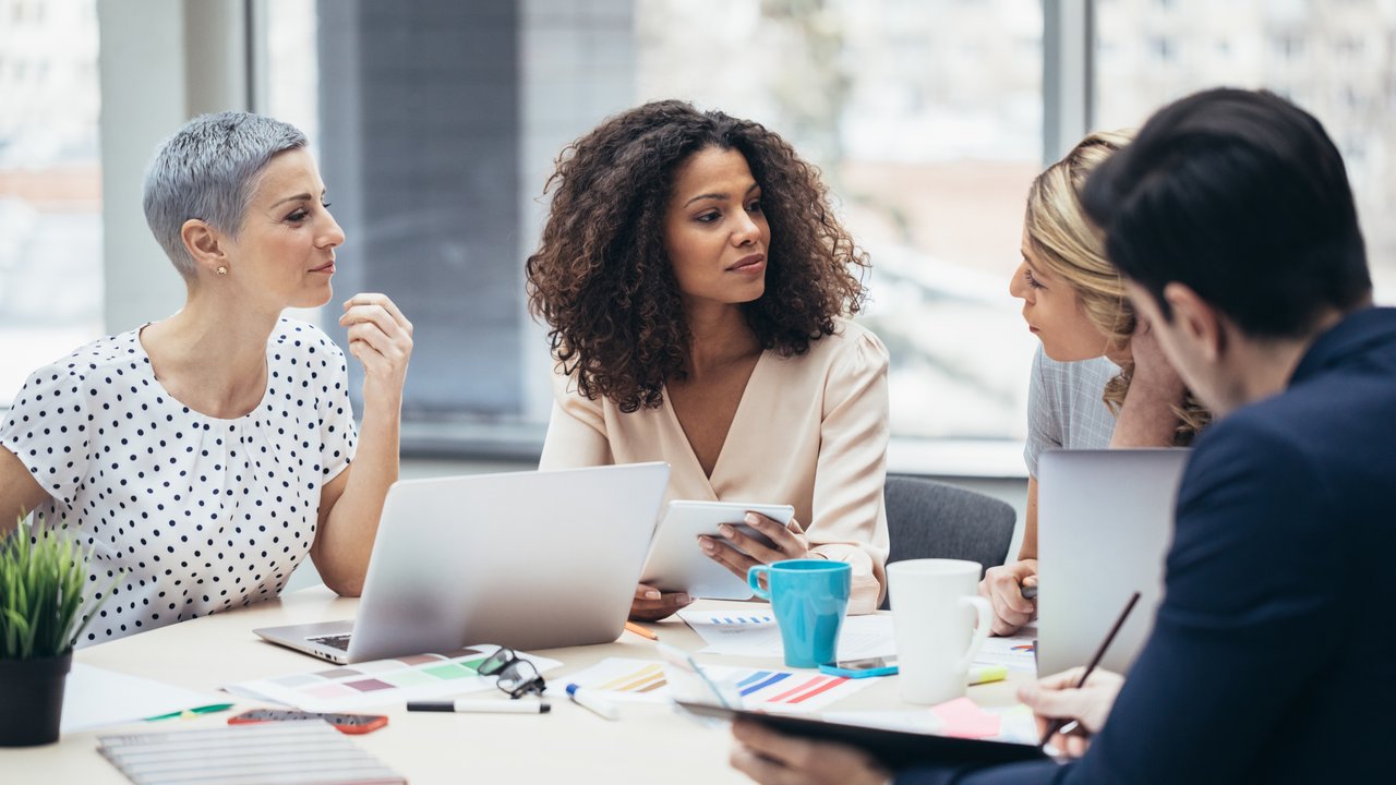 A Group of businesspeople sitting in meeting and listening to female colleague