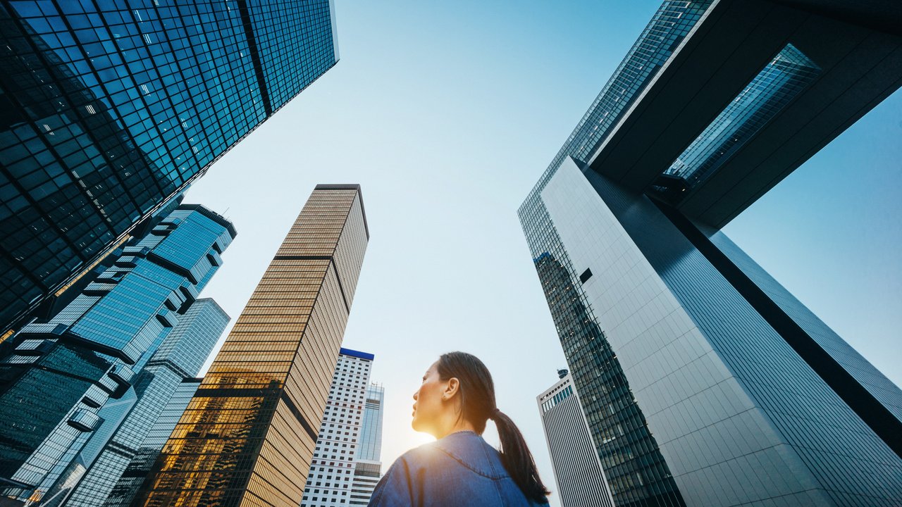 RiskScan 2024 – what are insurance buyers' and sellers' top risk concerns? Woman standing against modern skyscrapers in city