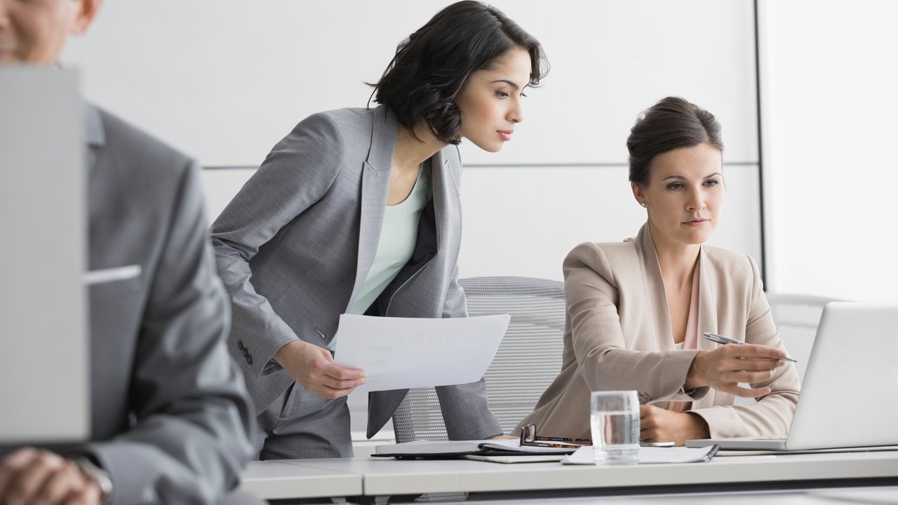 Businesswomen working at laptop in conference room.