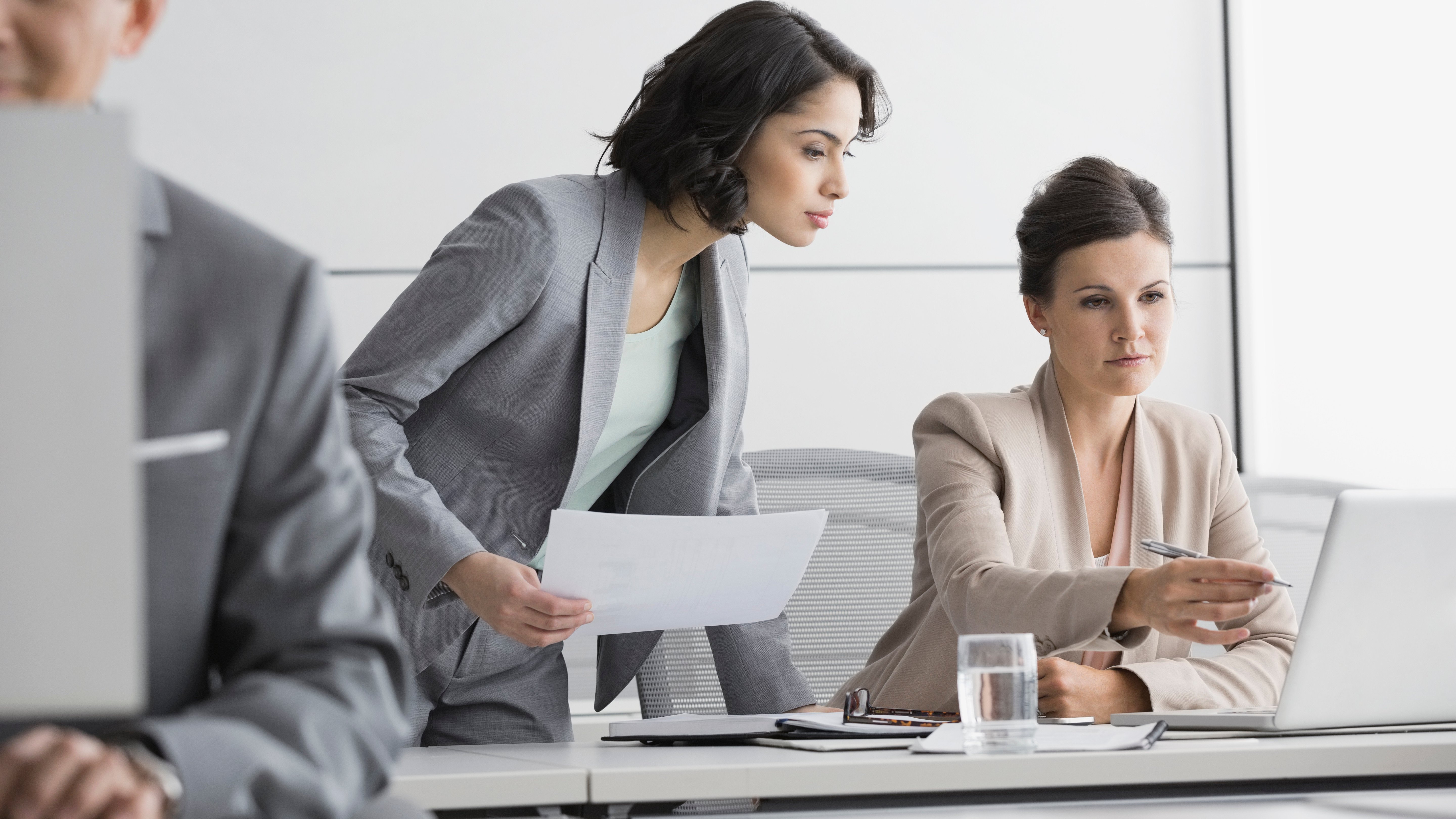 Businesswomen working at laptop in conference room.