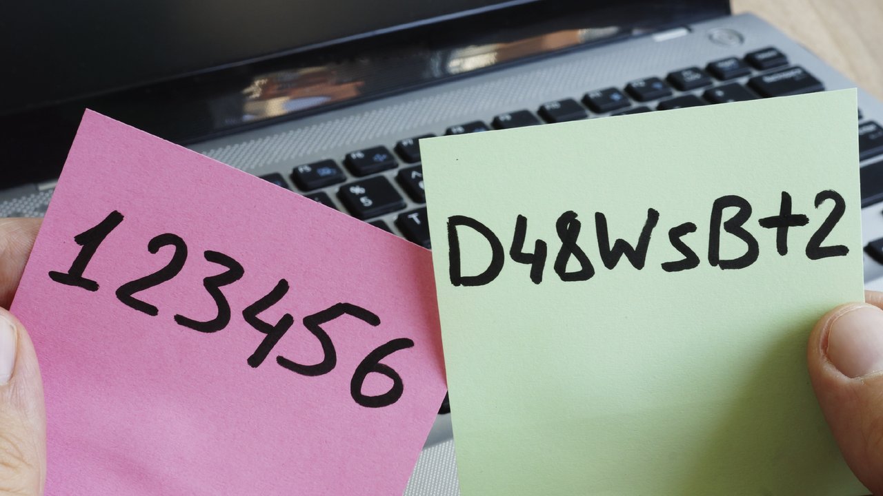 Hands holding weak and strong passwords on post-its