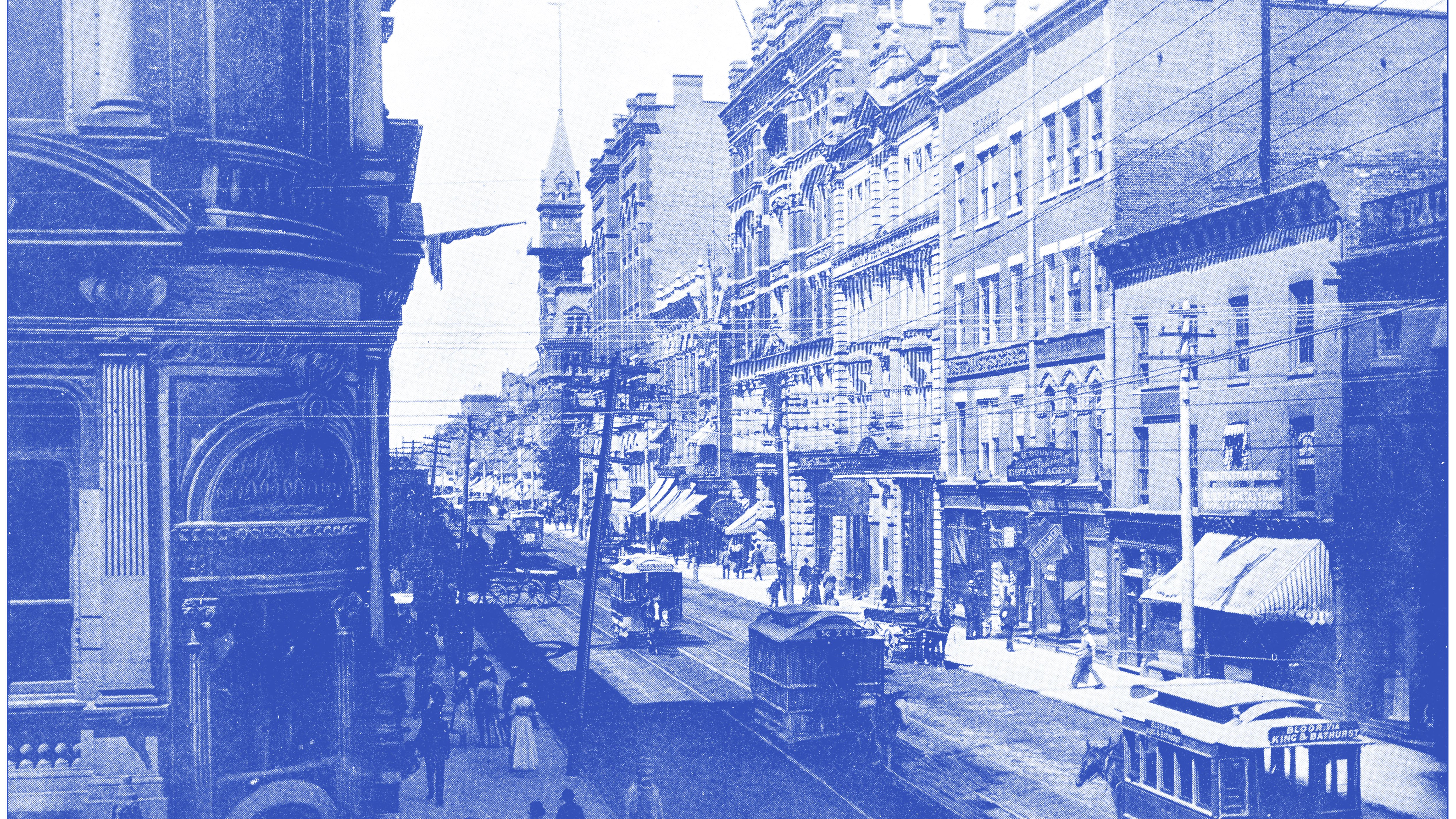 A bustling urban street scene features historic buildings with ornate architecture, some displaying signs for businesses. Streetcars travel along the tracks, while pedestrians stroll on the sidewalks. Flags hang from the buildings, adding a festive touch. The image is rendered in a blue tint, enhancing its vintage feel.