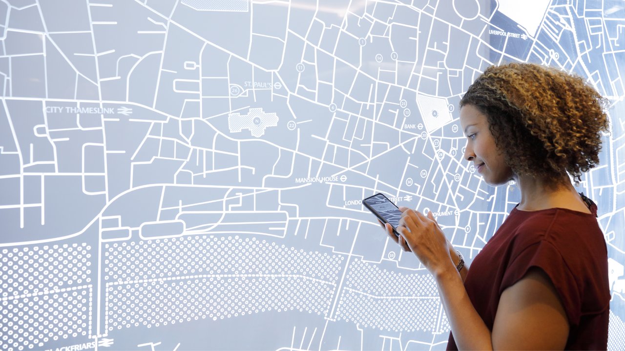 Woman using smartphone next to a futuristic digitally generated display