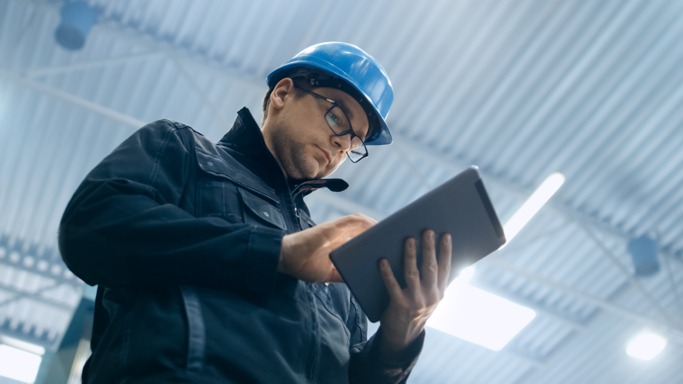An inspector wearing a hard hat and holding a tablet