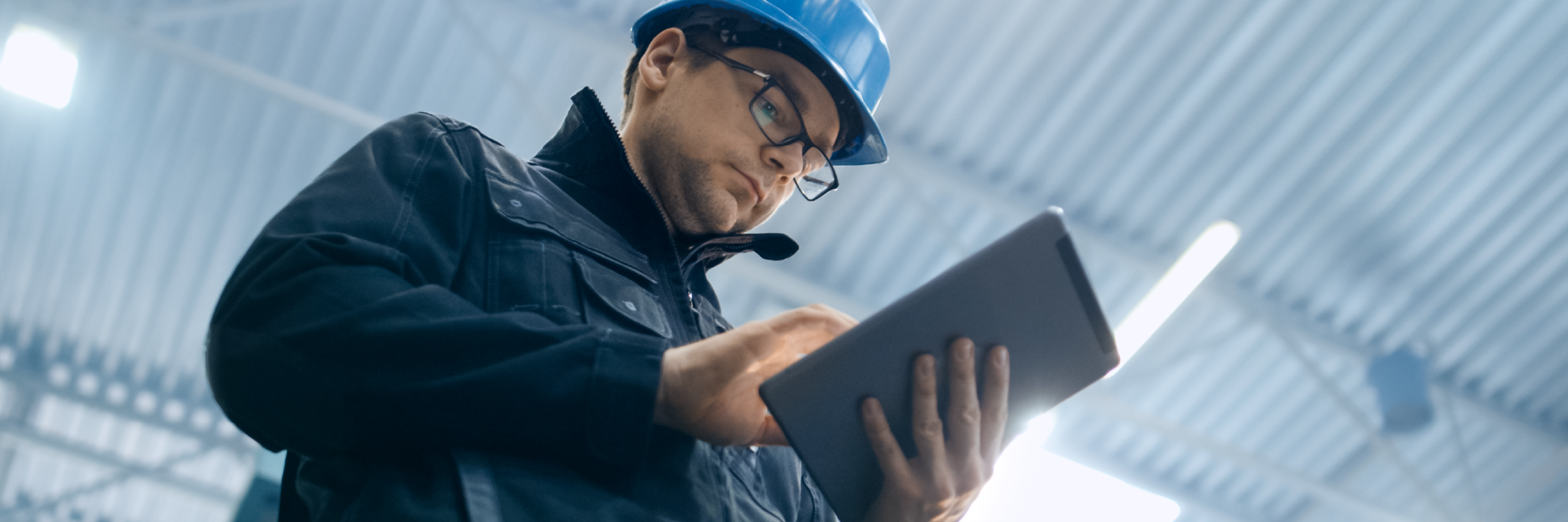 An inspector holding a tablet and wearing a hard hat